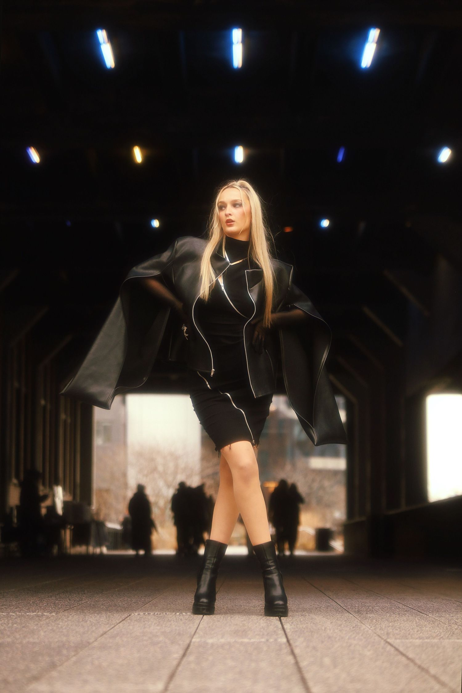 A figure in a black outfit with knee-high boots poses in dynamic sequence across a dark indoor space.