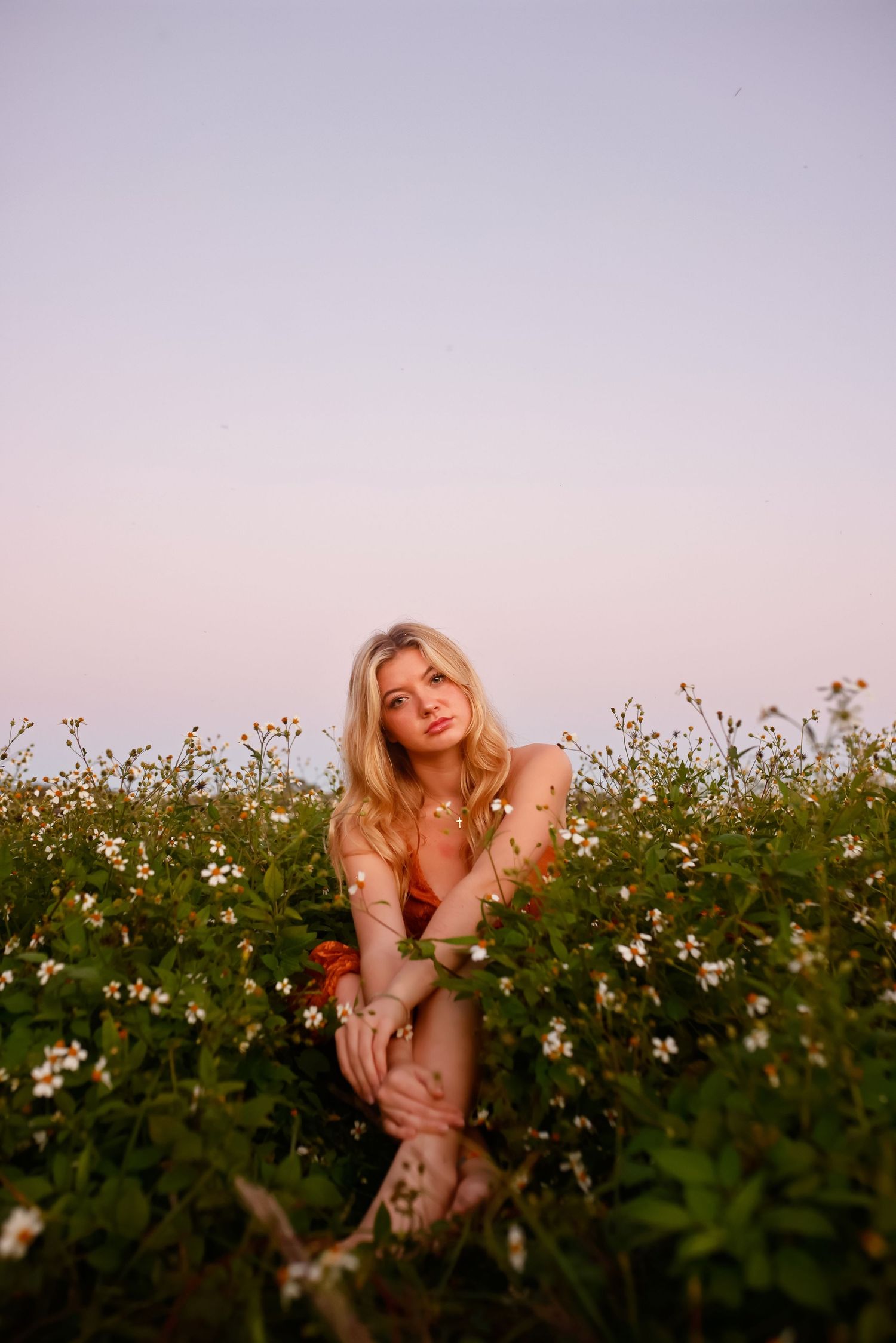 A figure poses gracefully in a blooming wildflower field during golden hour sunset.