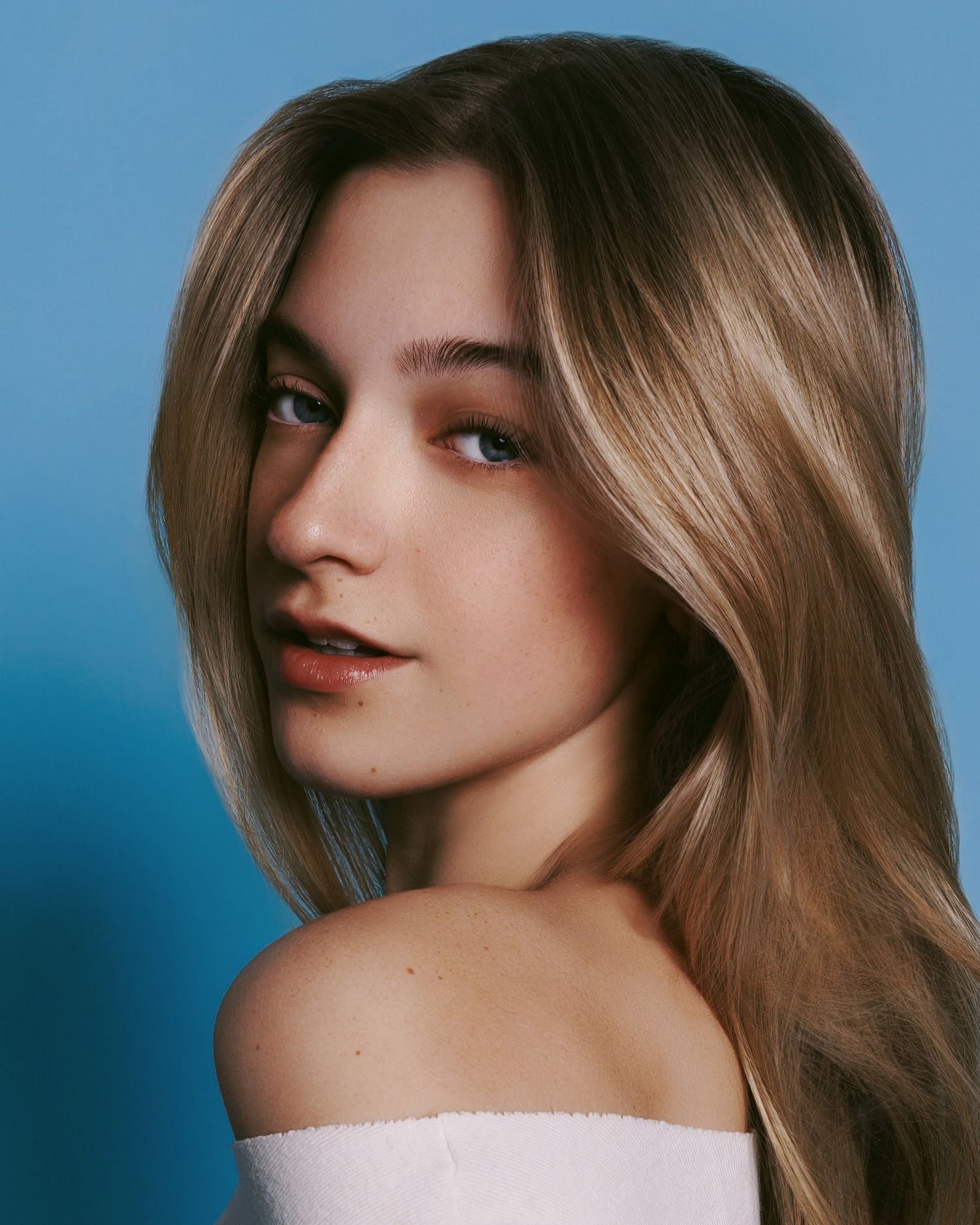 Close-up portrait series in front of blue backdrop showing different poses and angles of the same subject.