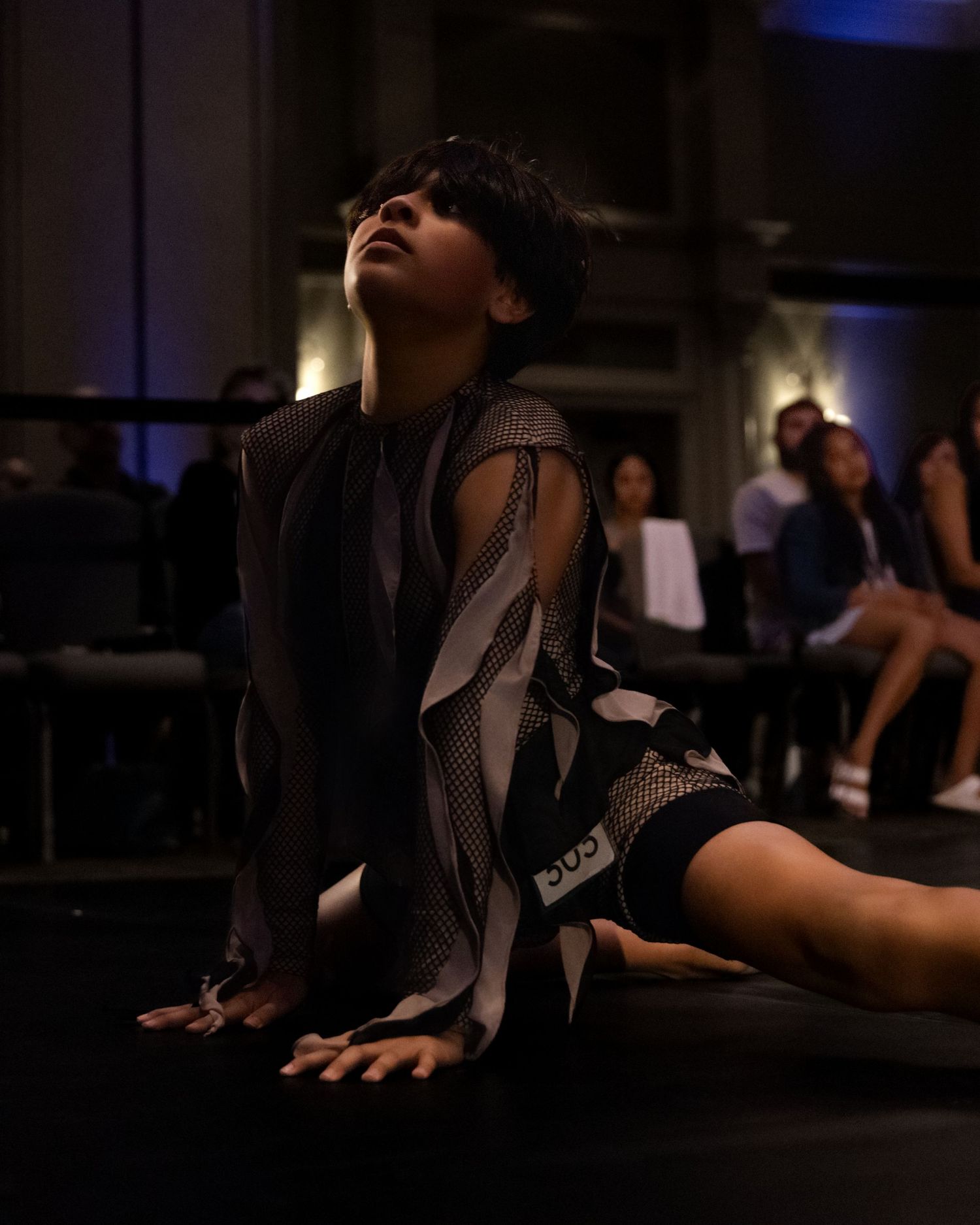 Dancers perform a contemporary piece in a dimly lit studio with dramatic lighting and expressive movements.