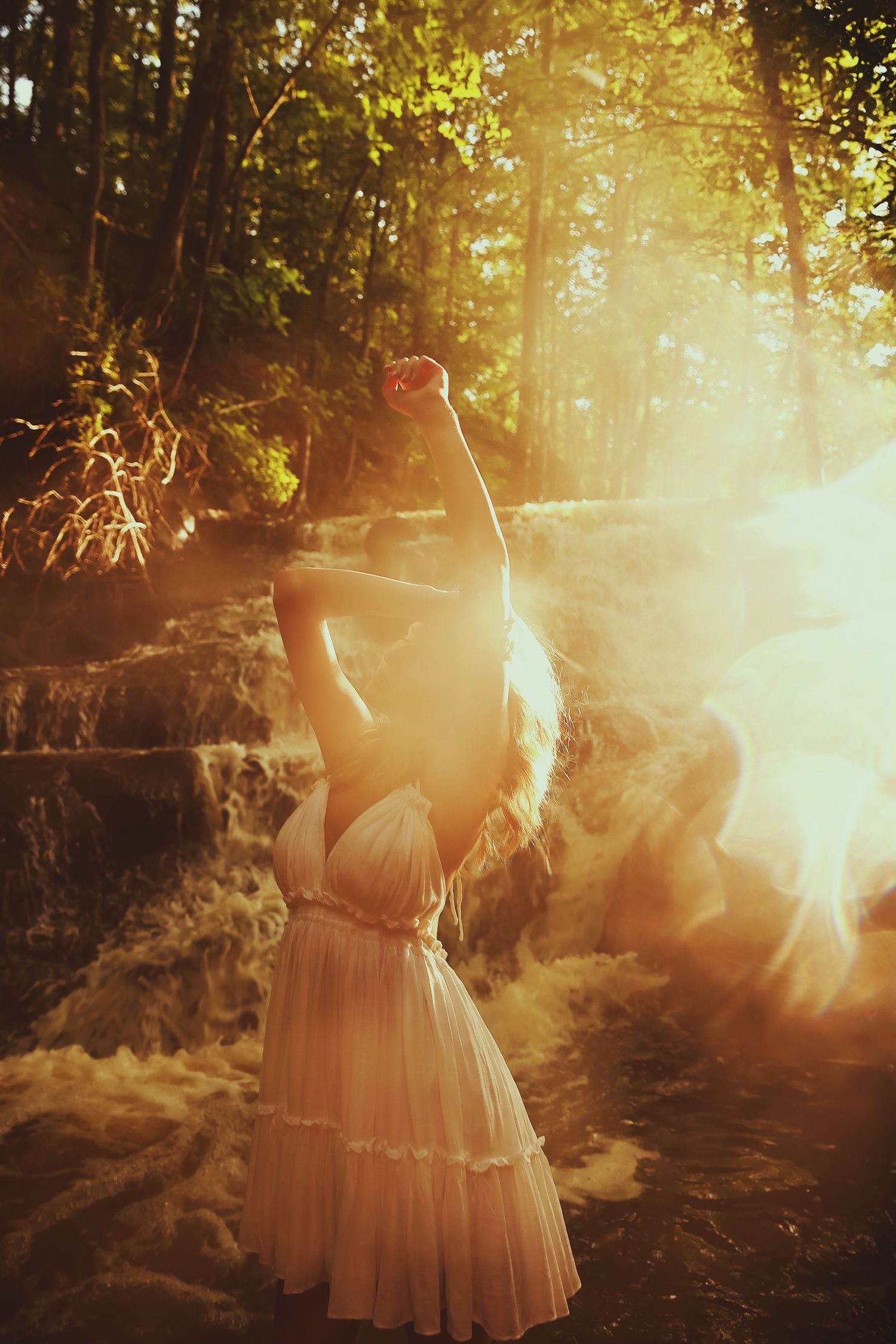 A dreamy forest scene with sunlight streaming through trees illuminating a figure in a flowing pink dress.