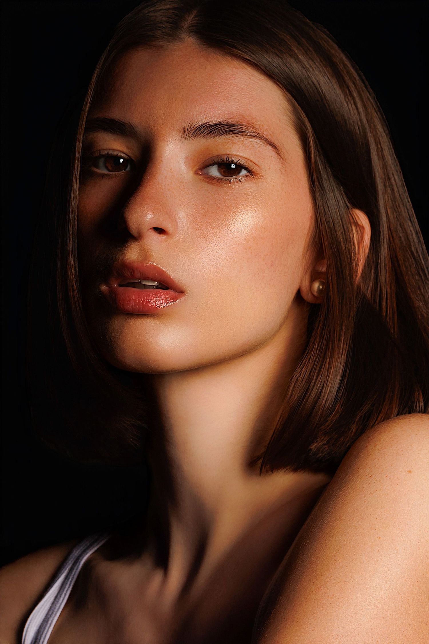 Portrait photo with dramatic lighting highlighting glowing skin and red lips against dark background.