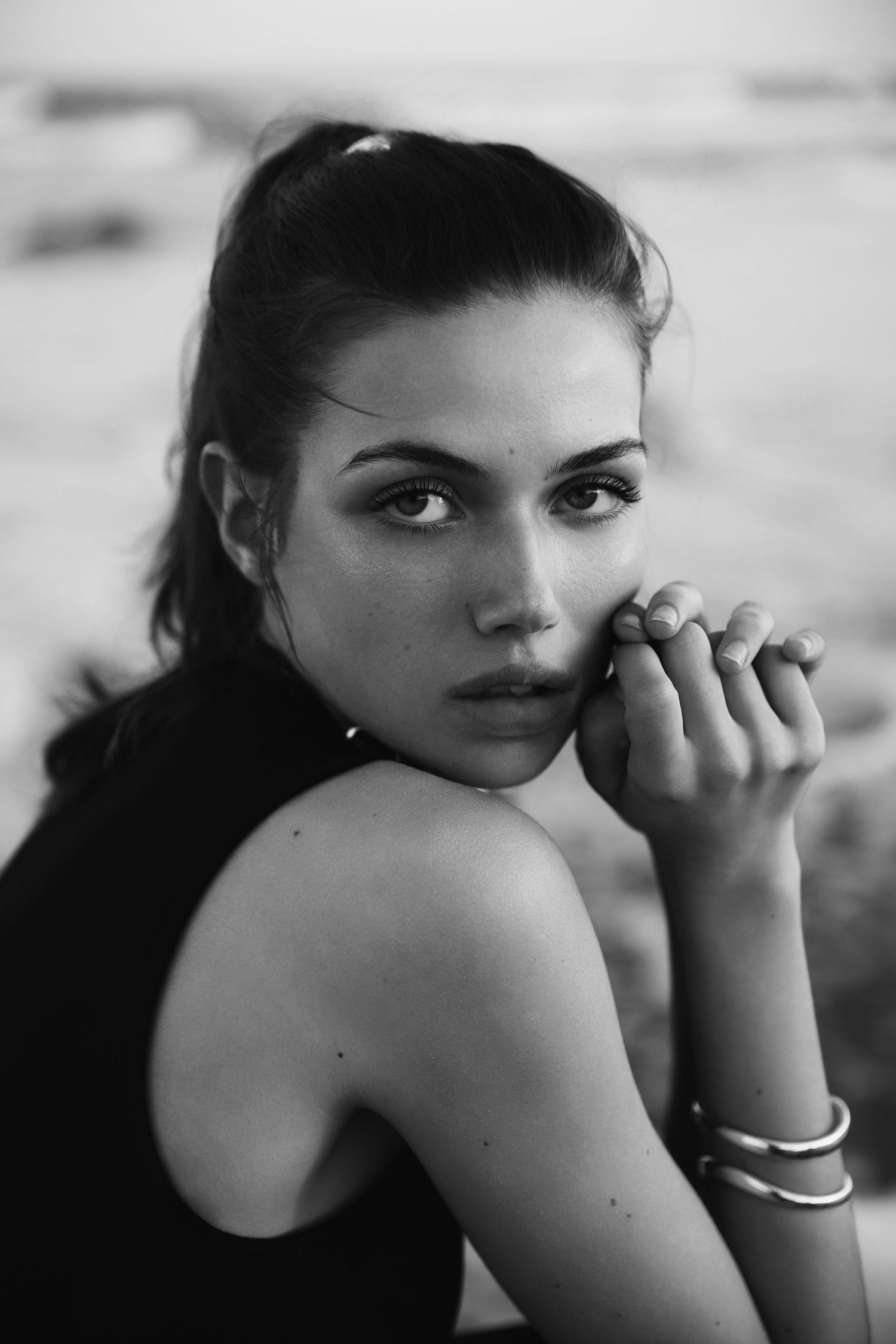 A black and white photo series showing a person in different poses looking over their shoulder with a silver bracelet.