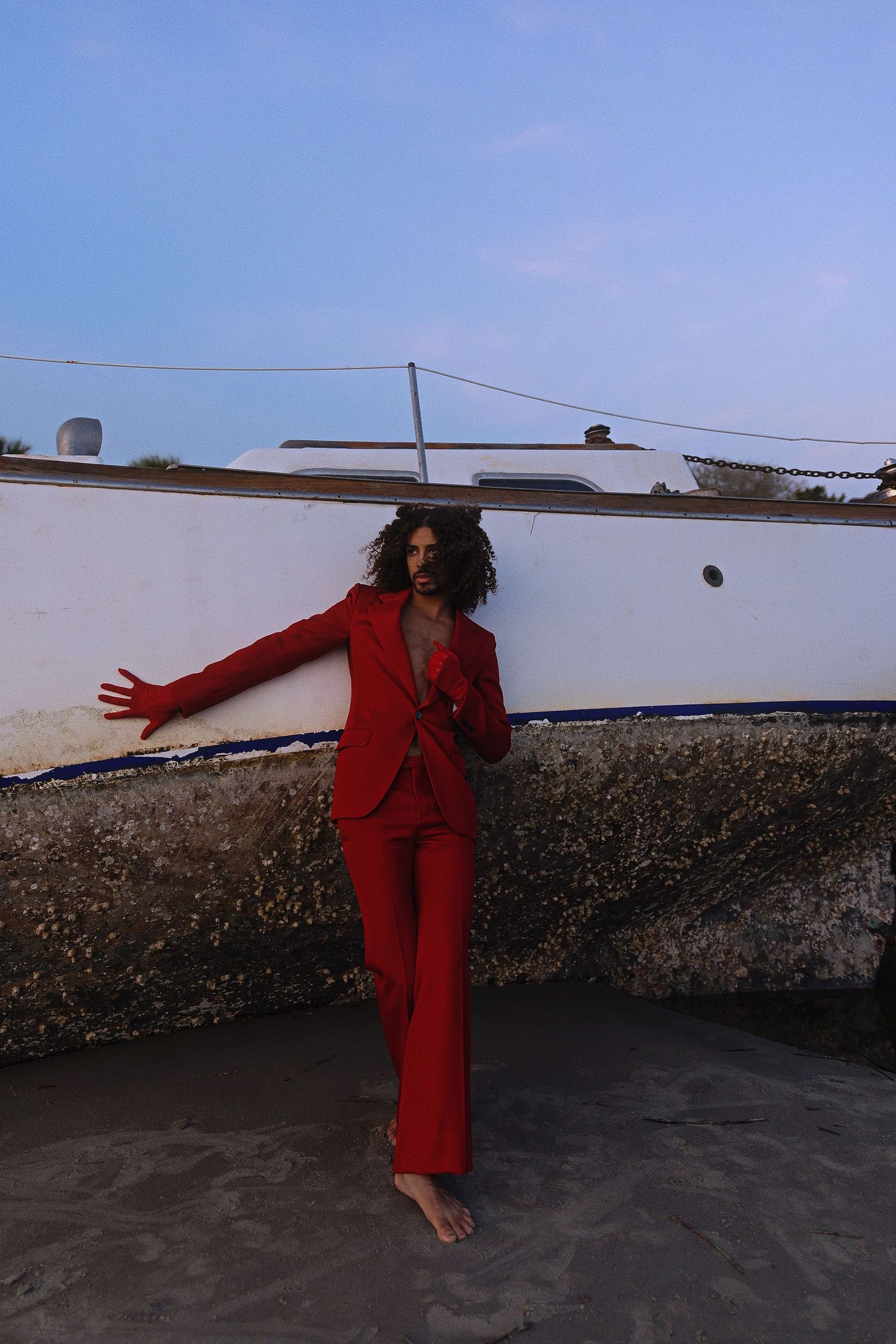 A person in a red outfit performs a graceful flowing movement sequence on a rooftop at dusk.
