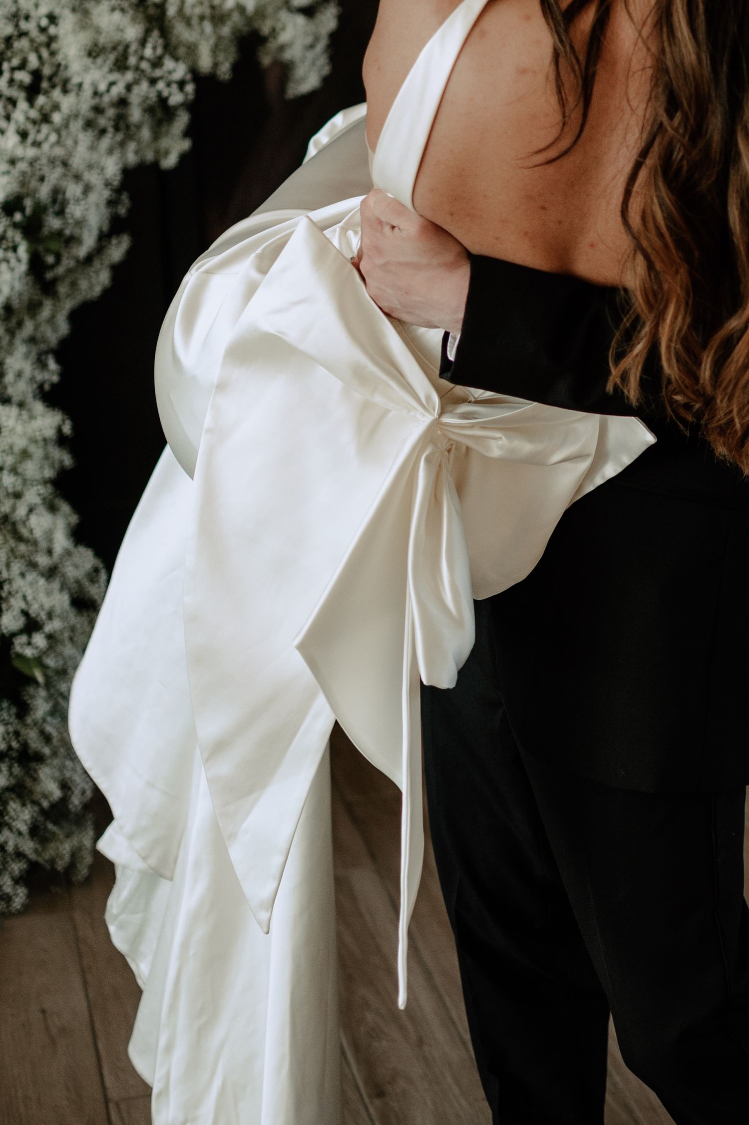 Close-up of a black and white evening gown featuring an elegant white bow detail and ruffled fabric draping.