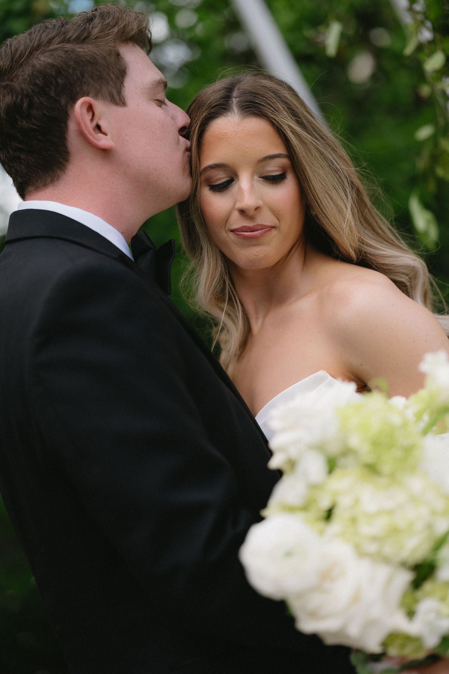Romantic wedding couple shares tender moments in a progression of intimate poses with white flowers in foreground.