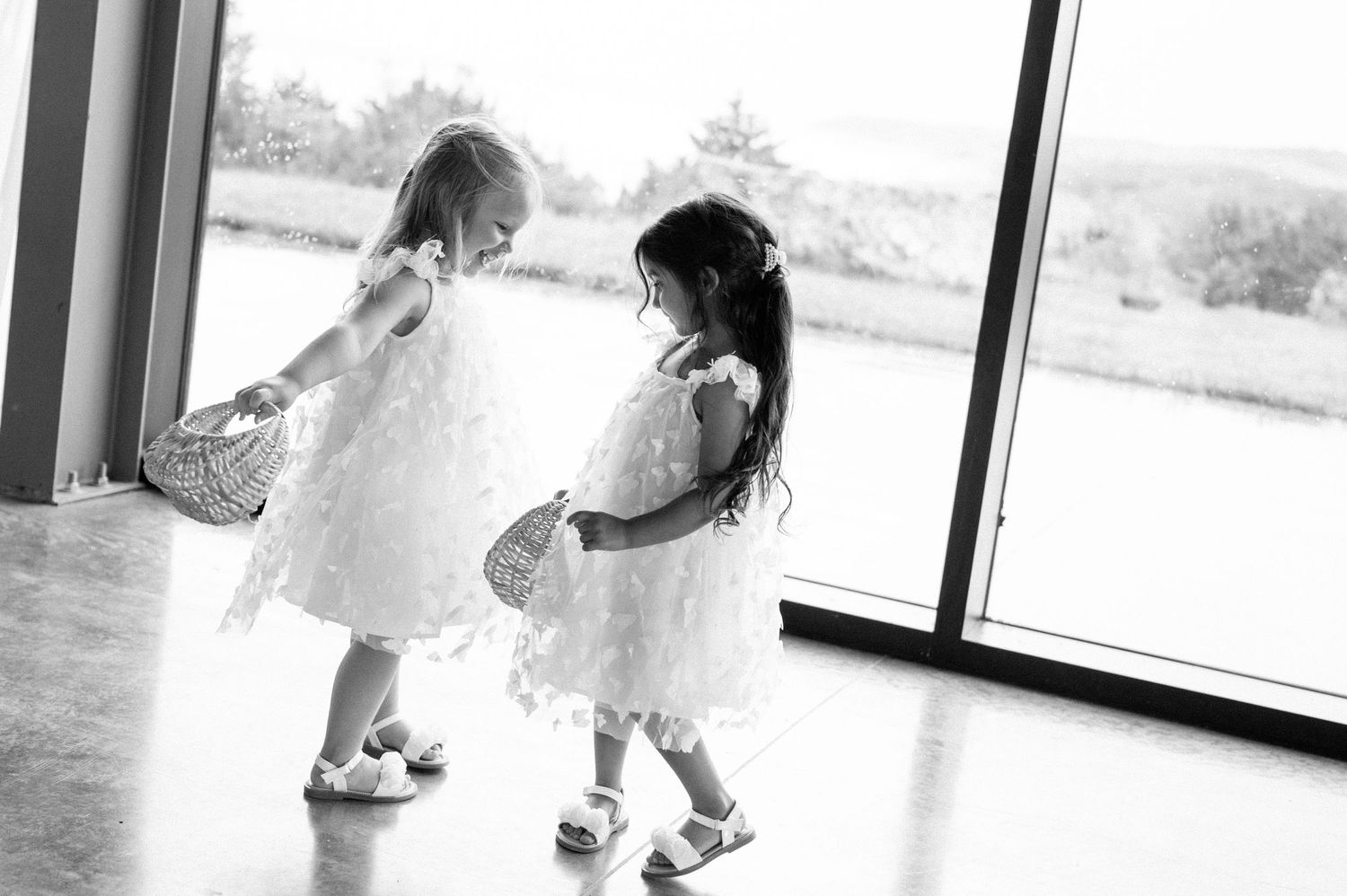 Four sequential black and white photos show a toddler spinning and twirling in a dress near a window.