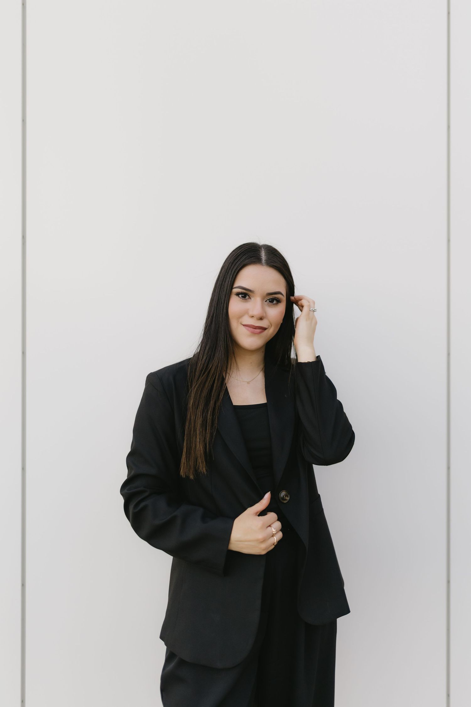 Person in all black business attire poses confidently against white background in professional photoshoot.