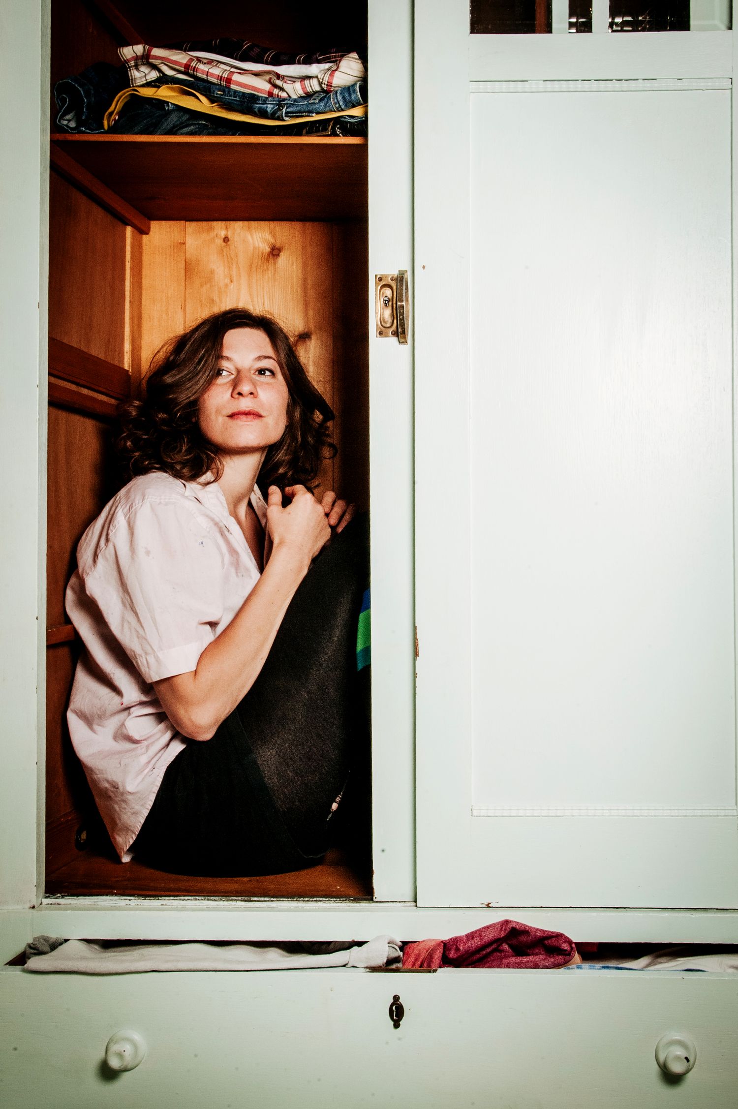 Fotografie von Jenny Jacoby: Frau in unordentlichem Schlafzimmer am Kleiderschrank. Authentische Alltagsszene. Künstlerporträt