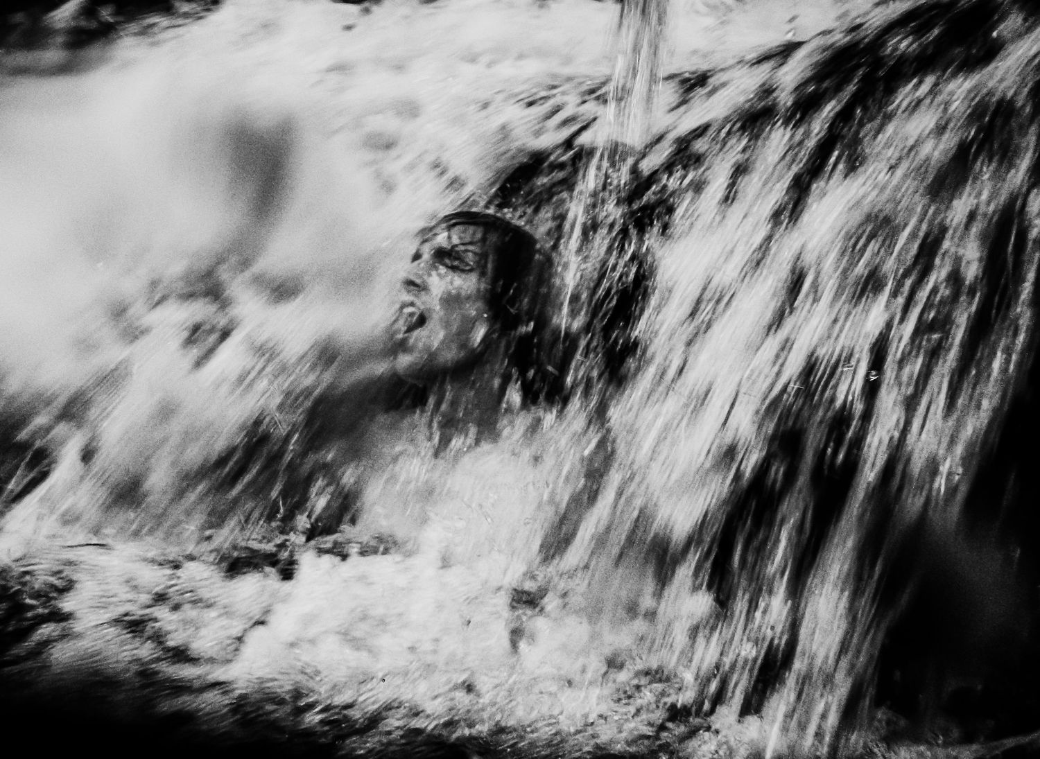 Künstlerisches Schwarzweiß-Porträt einer Person unter Wasserfall – intensiver Ausdruck, Bewegung und Emotion.
