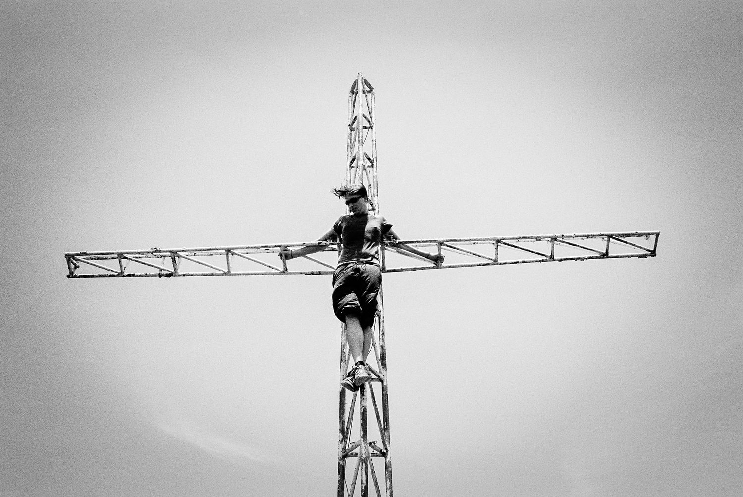 Person auf Funkturm in Kreuzpose, karikaturhafte Darstellung von Jesus am Kreuz, symbolische und humorvolle Interpretation