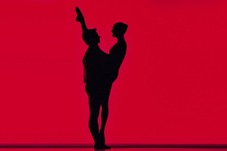 Ballett-Fotografie von Jenny Jacoby: Tänzer-Silhouette in klassischer Pose vor leuchtendem roten Hintergrund.