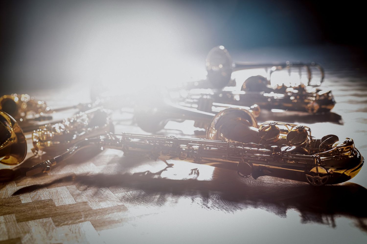 Mehrere Saxophone im Bühnenlicht auf Holzboden, fotografiert von Jenny Jacoby – goldene Reflexe und ruhige Atmosphäre.