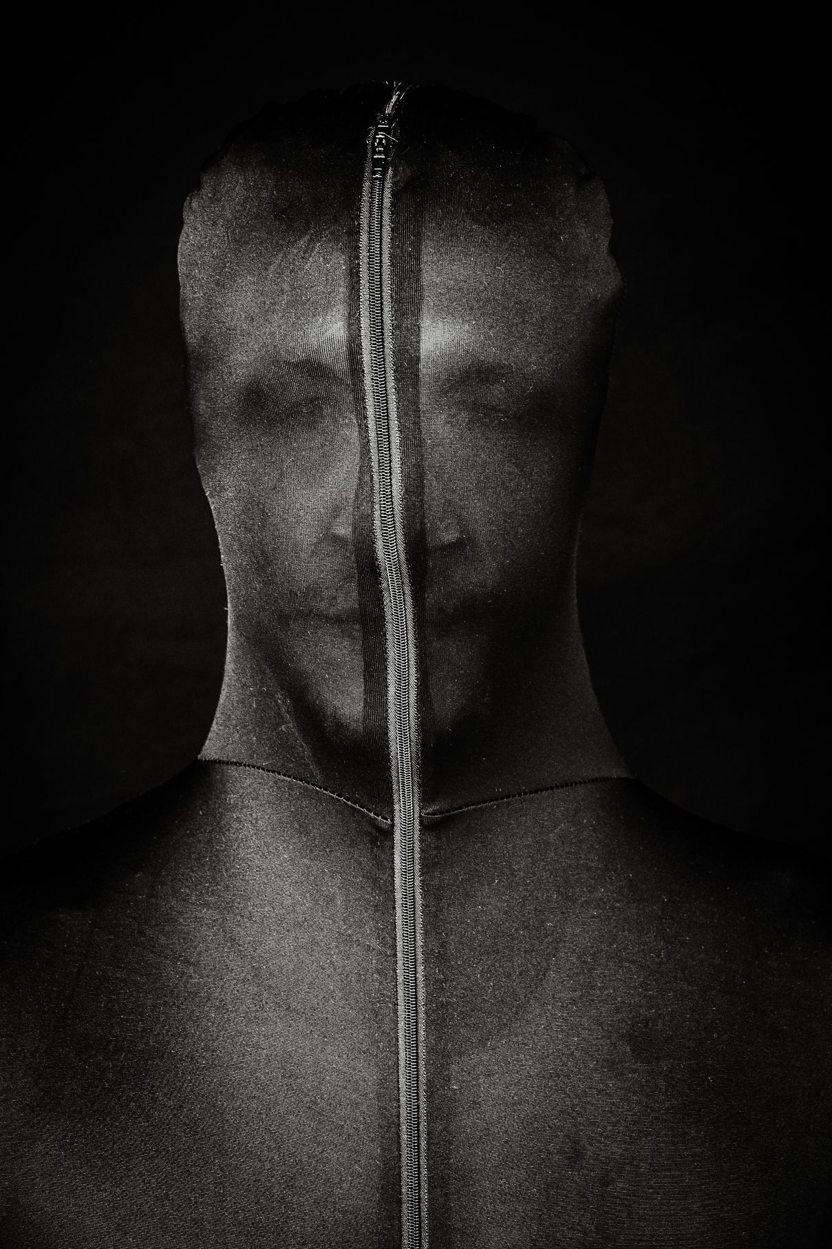 Künstlerisches Schwarzweißporträt eines Mannes mit verdecktem Gesicht – ein Spiel mit Identität, Nähe und Distanz. Foto: Jenny Jacoby.