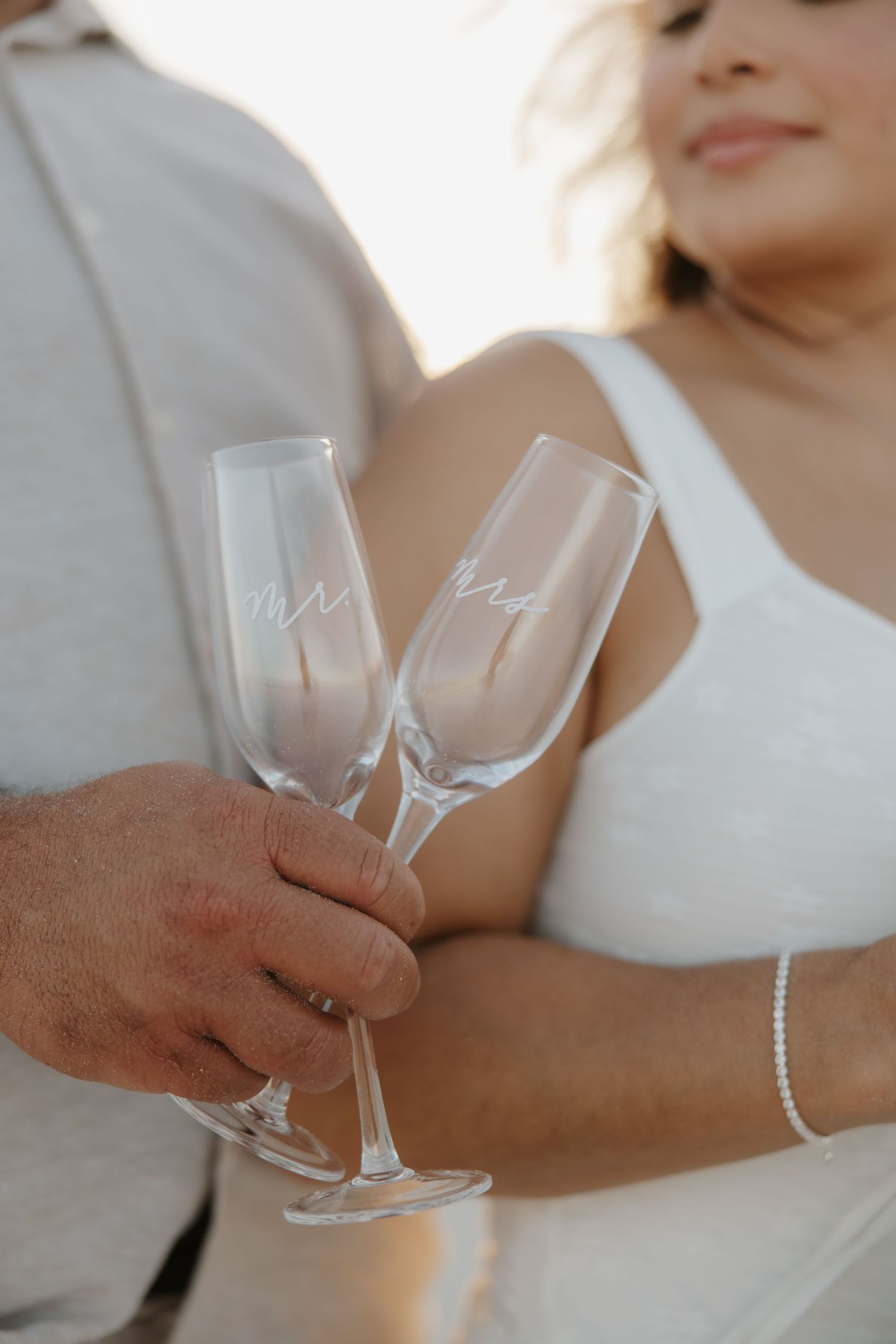 Bride and groom holding personalized Mr and Mrs champagne flutes at their wedding celebration.