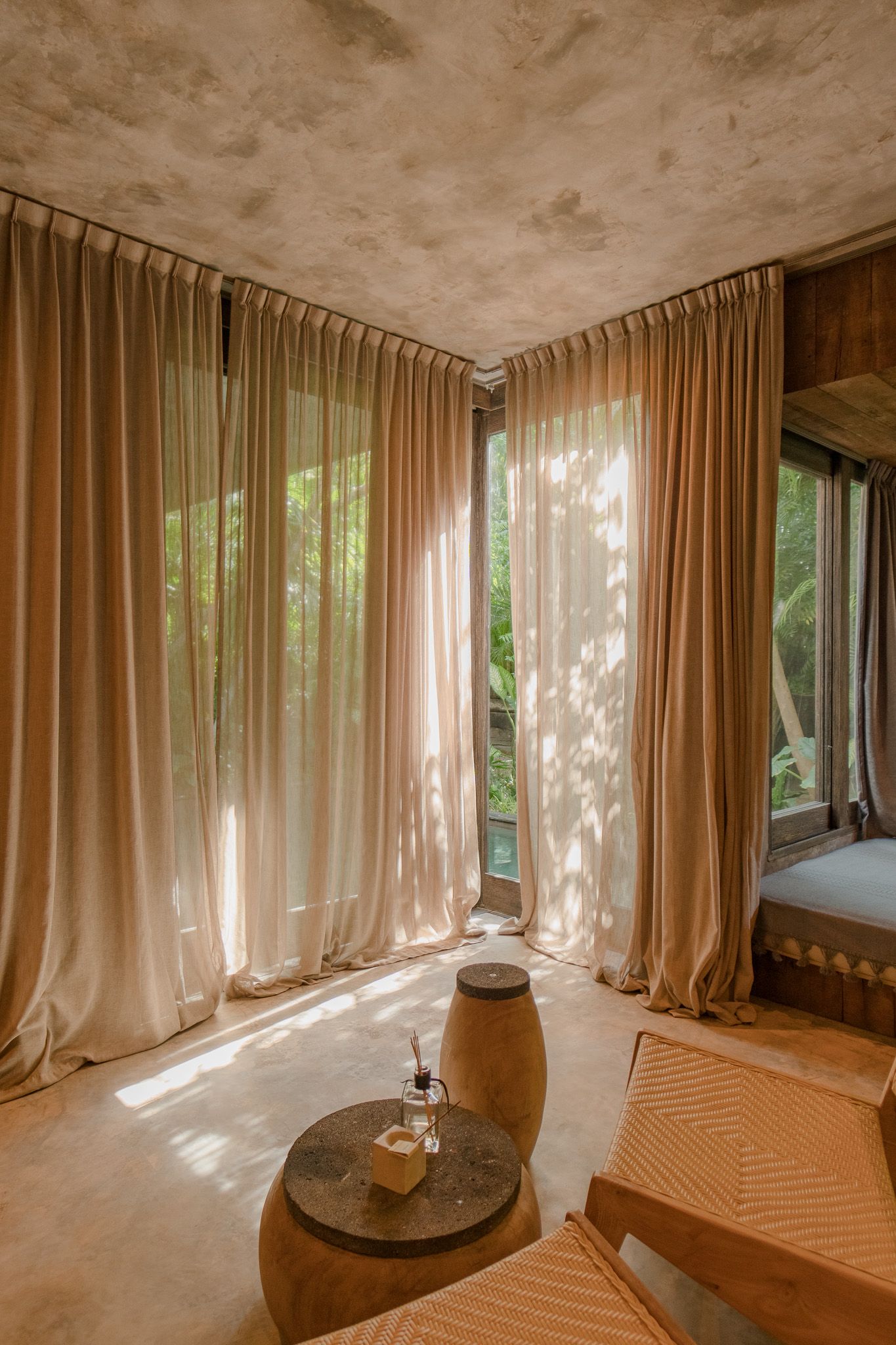 A serene spa room with flowing beige curtains and natural light filtering through large windows.