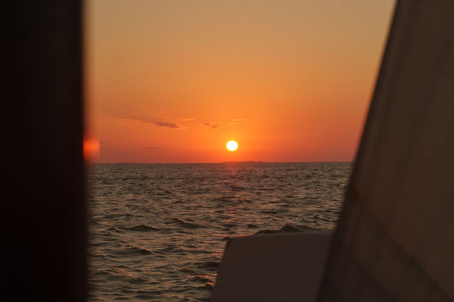 Vibrant orange sun setting over calm ocean waters creating a peaceful seascape horizon.