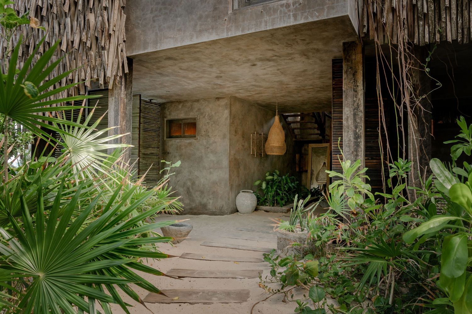 Tropical garden pathway with stone steps, hanging vines, and lush palm fronds creating a natural walkway.