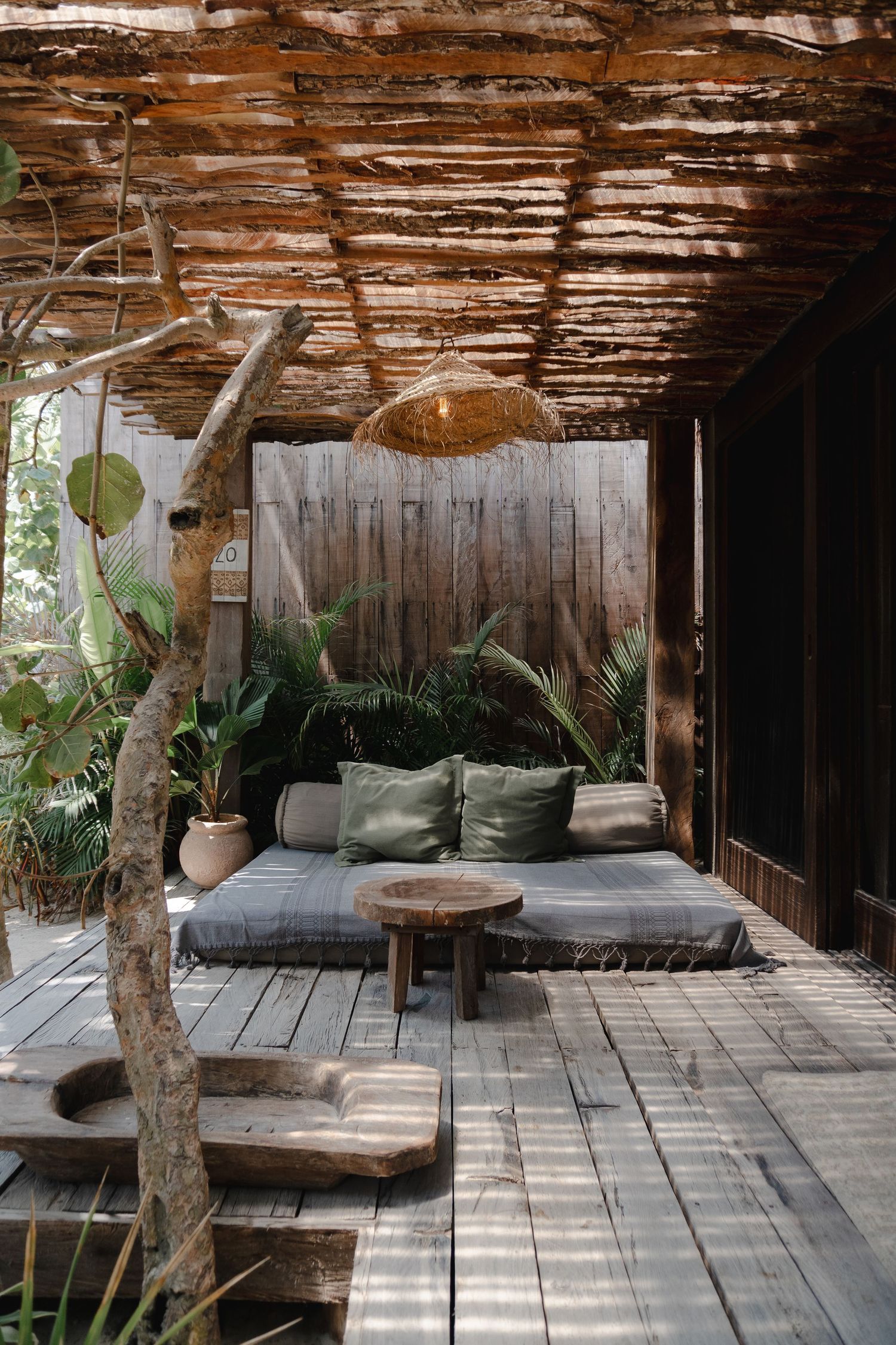 Outdoor lounge area with grey cushions and wooden beams creating a shaded retreat.