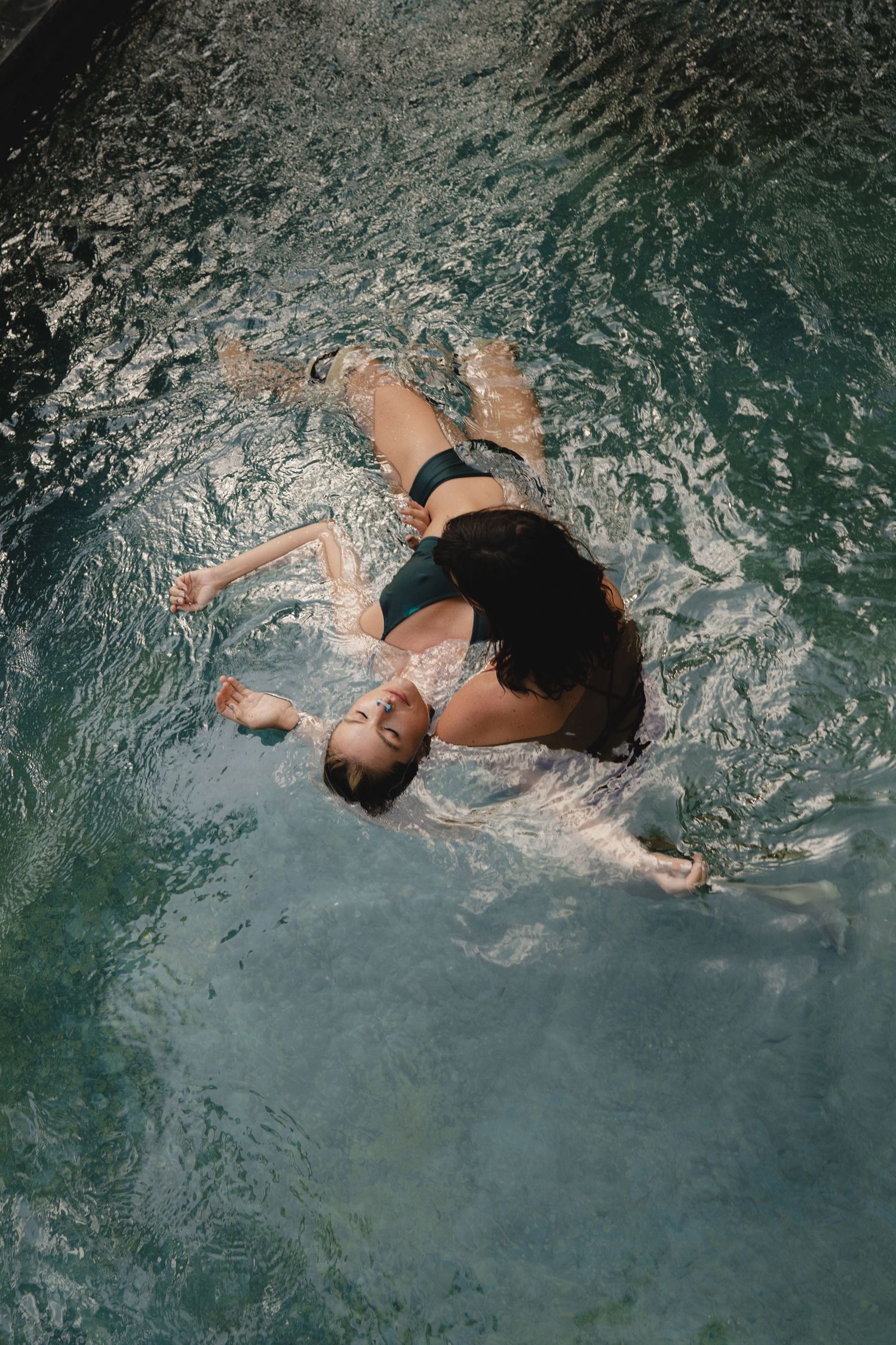 A sequence of backstrokes showing a swimmer gracefully moving through turquoise pool water.