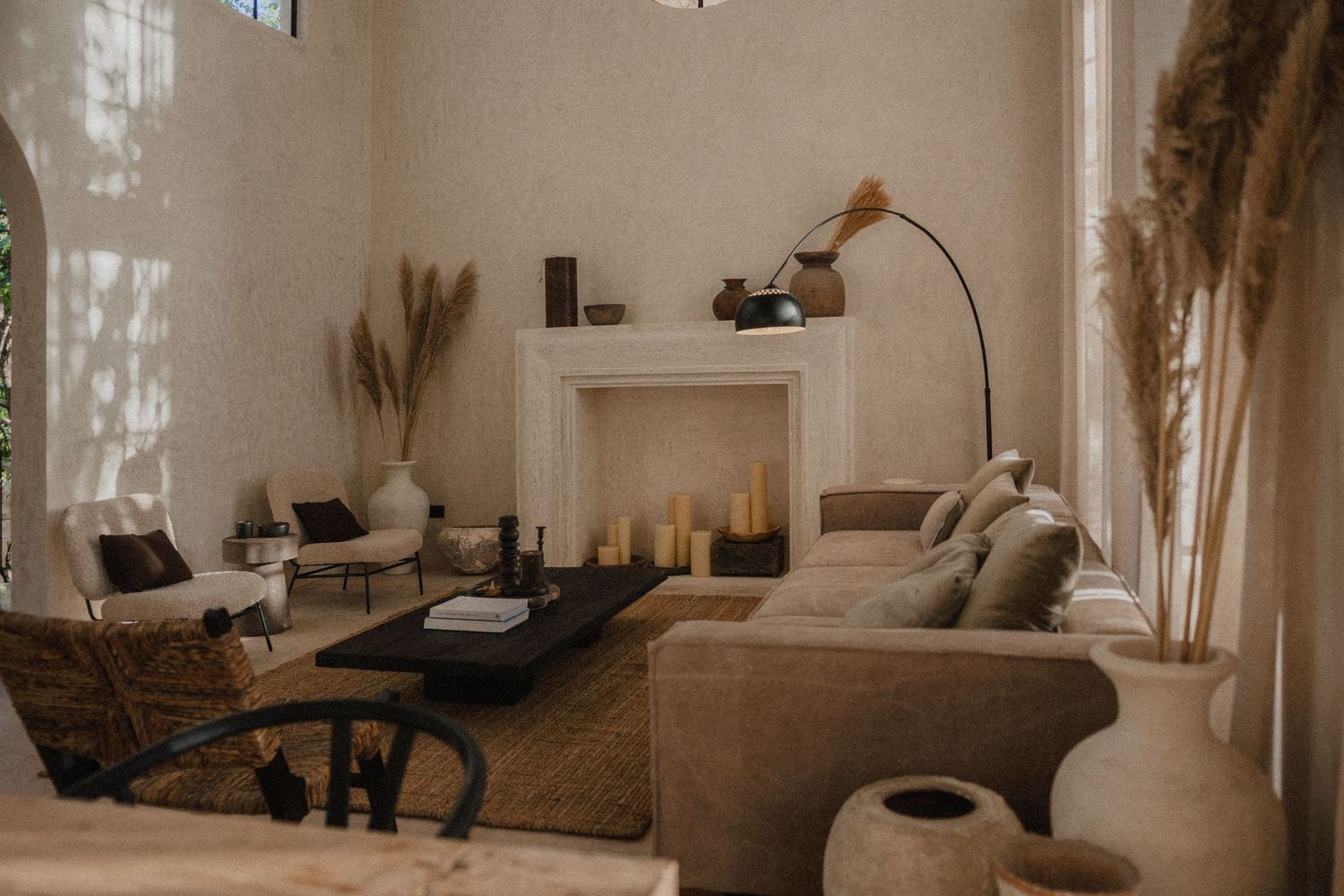 Minimalist beige living room interior with modern furniture, natural light, and decorative dried pampas grass accents.