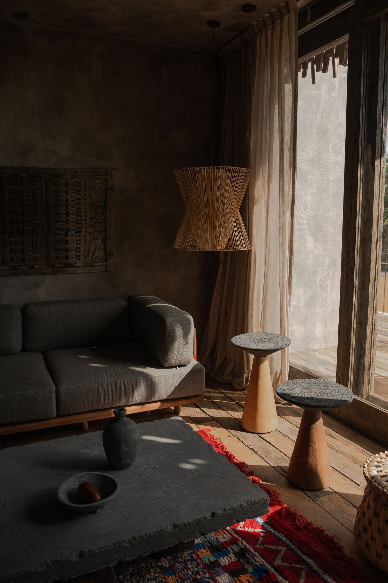 Minimalist living room interior with natural light streaming through large windows onto gray furniture.