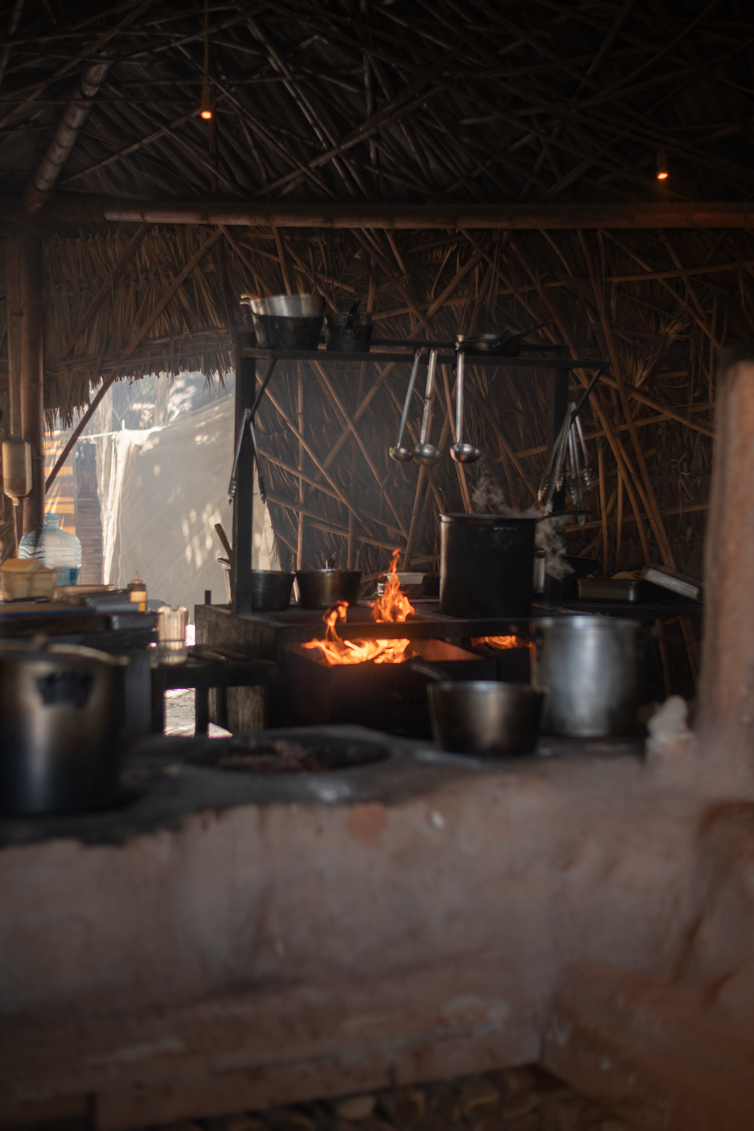 Dark rustic kitchen interior with pots and pans hanging in dim lighting.