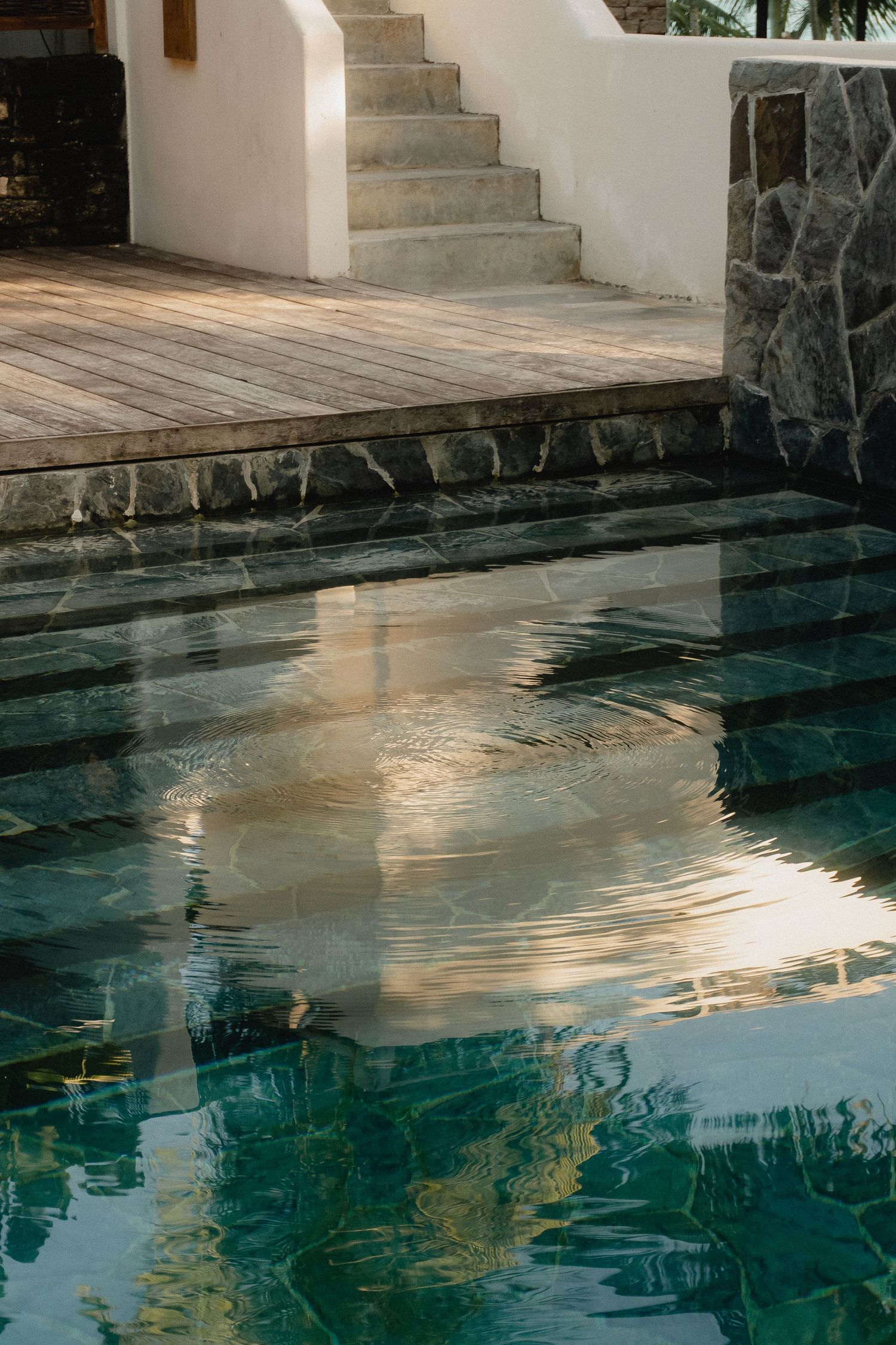 Tranquil indoor pool with stone walls reflects sunlight and architectural details in its calm turquoise waters.