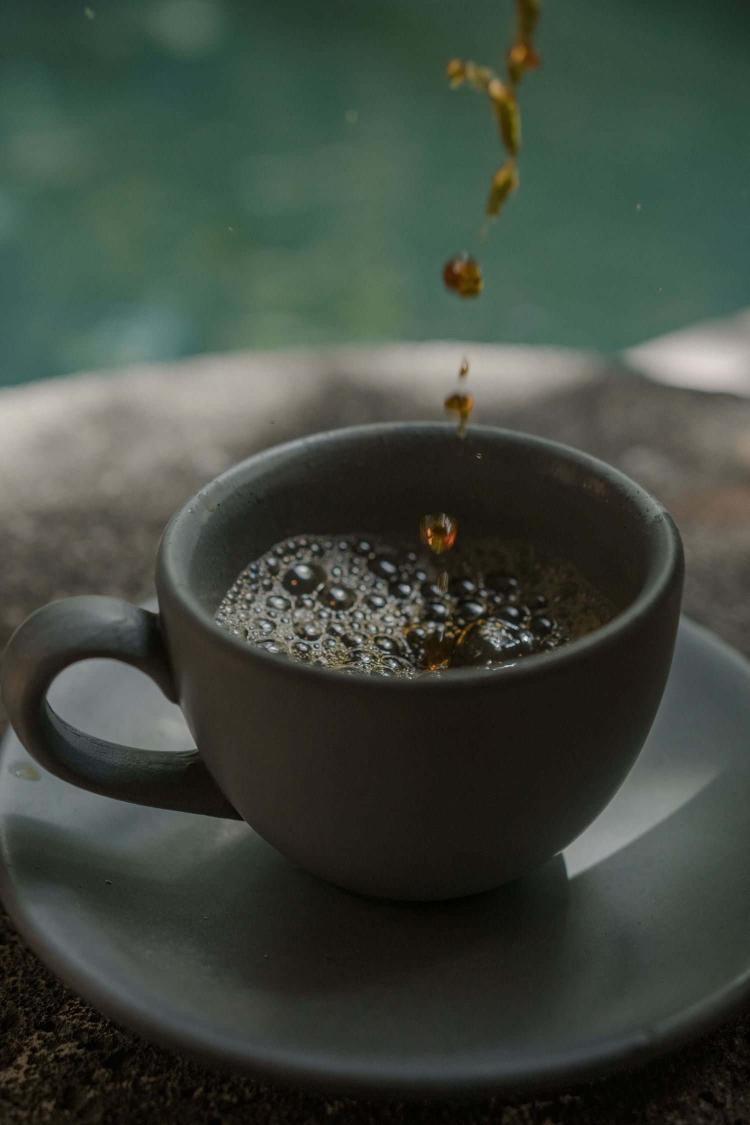 Coffee being poured into dark ceramic cup creating ripples in slow motion.