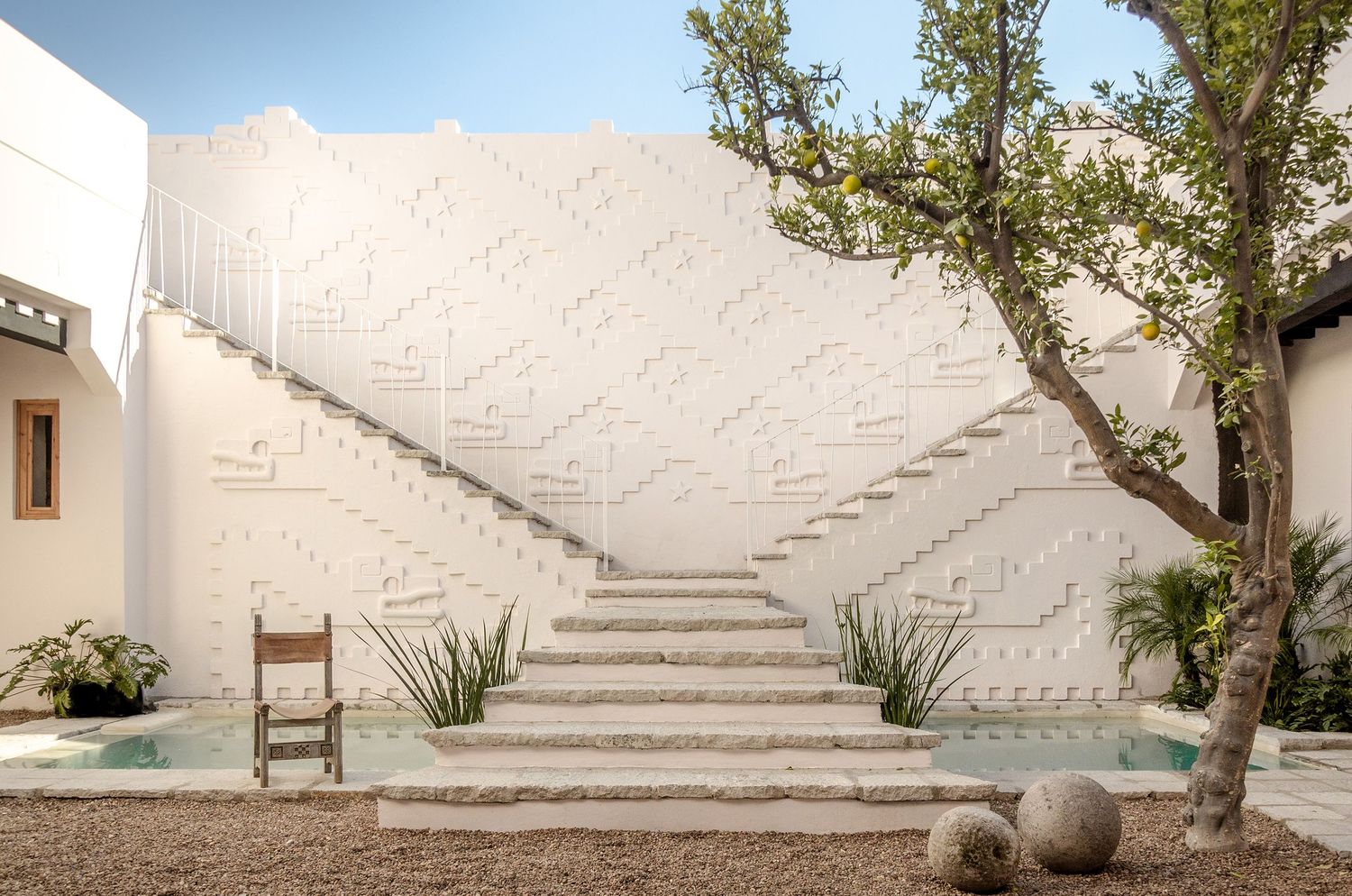 White stucco staircase with curved walls and potted plants creates a serene Mediterranean architectural setting.