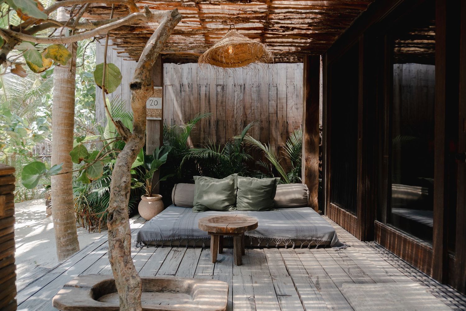 A cozy outdoor patio space with cushioned seating, wooden deck, and natural greenery creating a relaxing atmosphere.