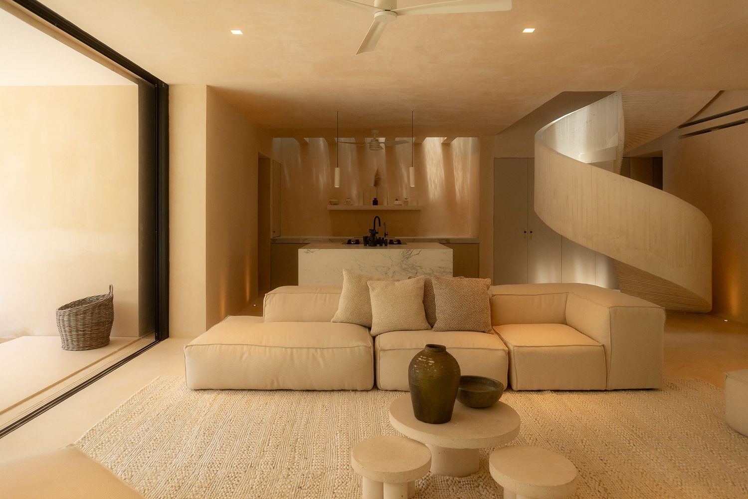 Modern minimalist living room with white walls, beige sofa, and recessed lighting creating a warm, inviting atmosphere.