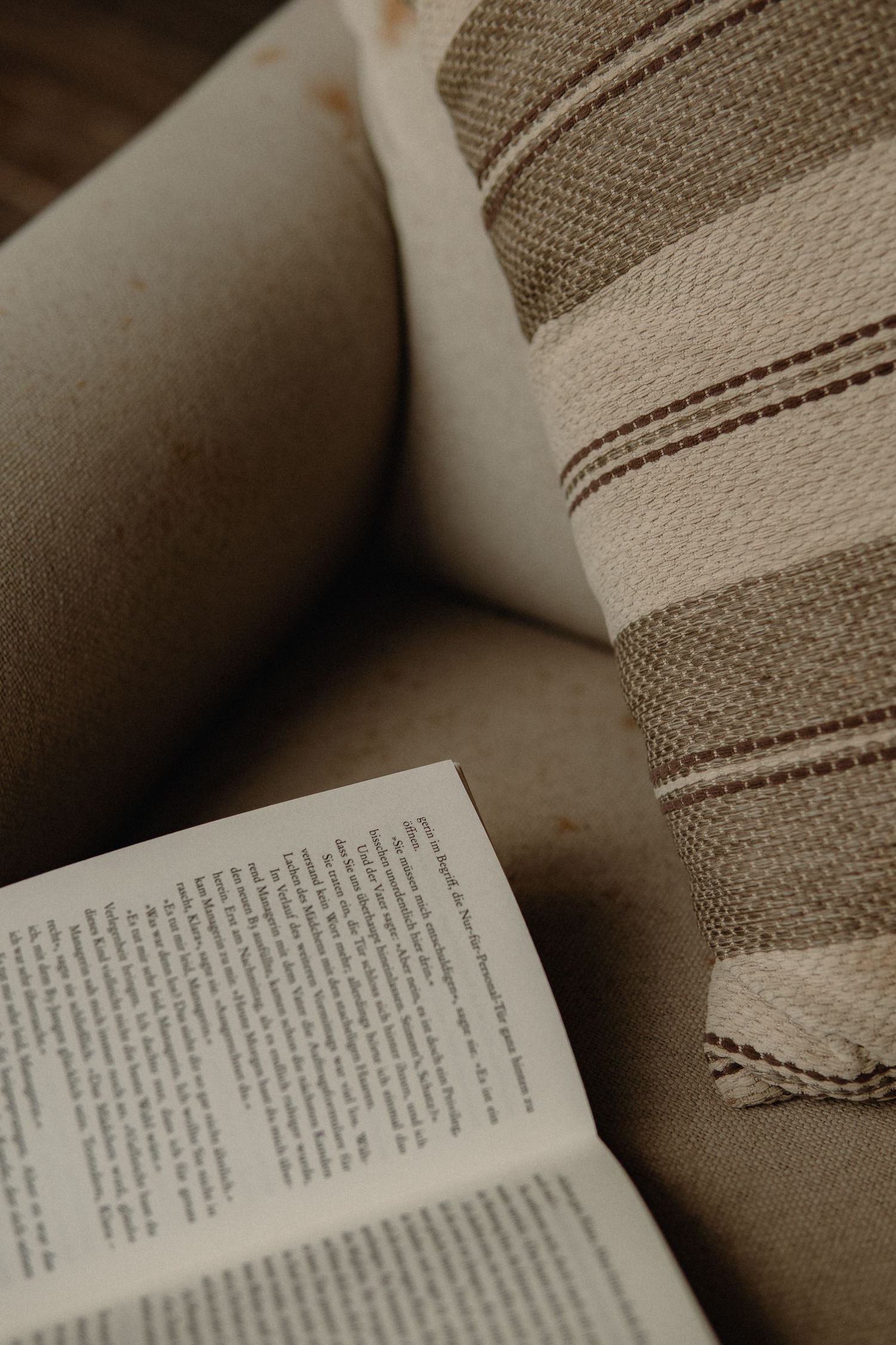 Open book with pages spread out on a textured fabric surface in sepia tones.