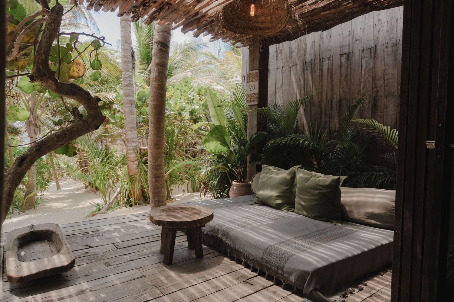 Rustic wooden spa retreat with bamboo walls and thatched roof features lounge chairs overlooking tropical greenery.