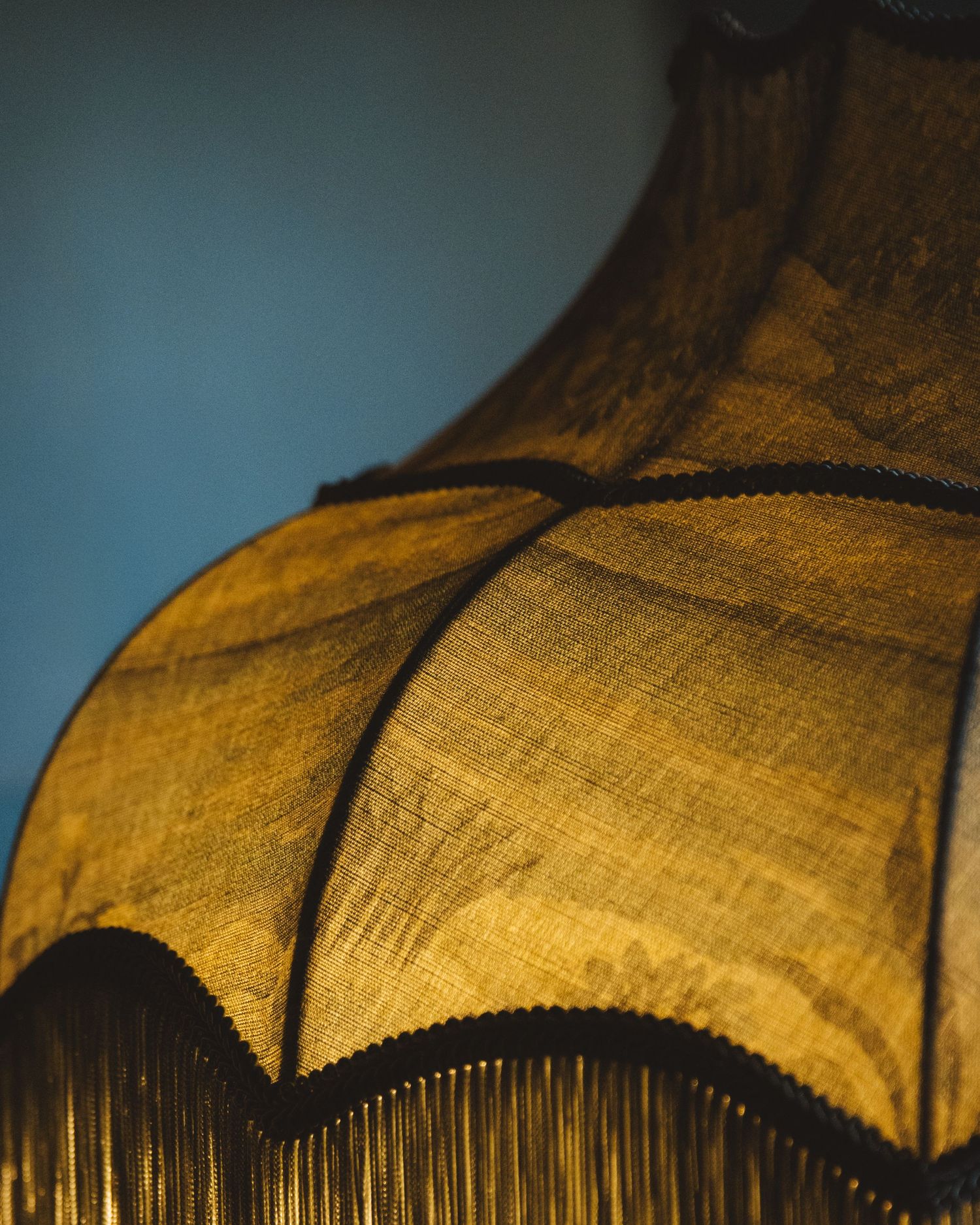 close up of green fringe lamp with blue background
