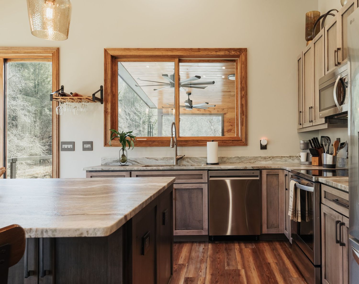 A kitchen sink with a large window overlooking the back deck.