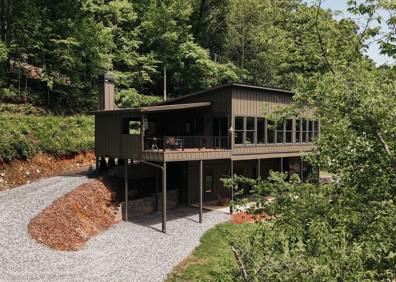 Arial Photo of a cabin on stilts showing a large amount of windows and a back deck.