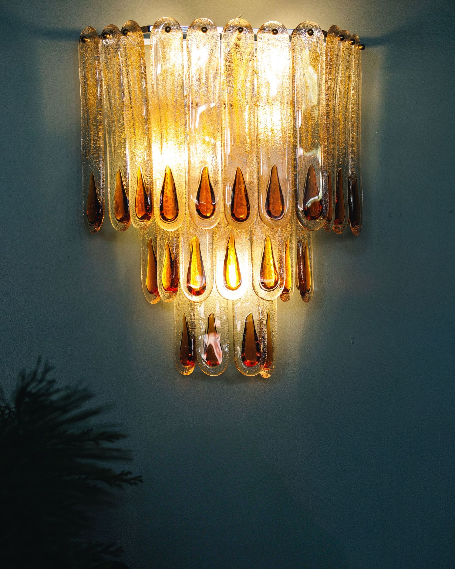 wall sconce made of glass panels with a green plan on the left side