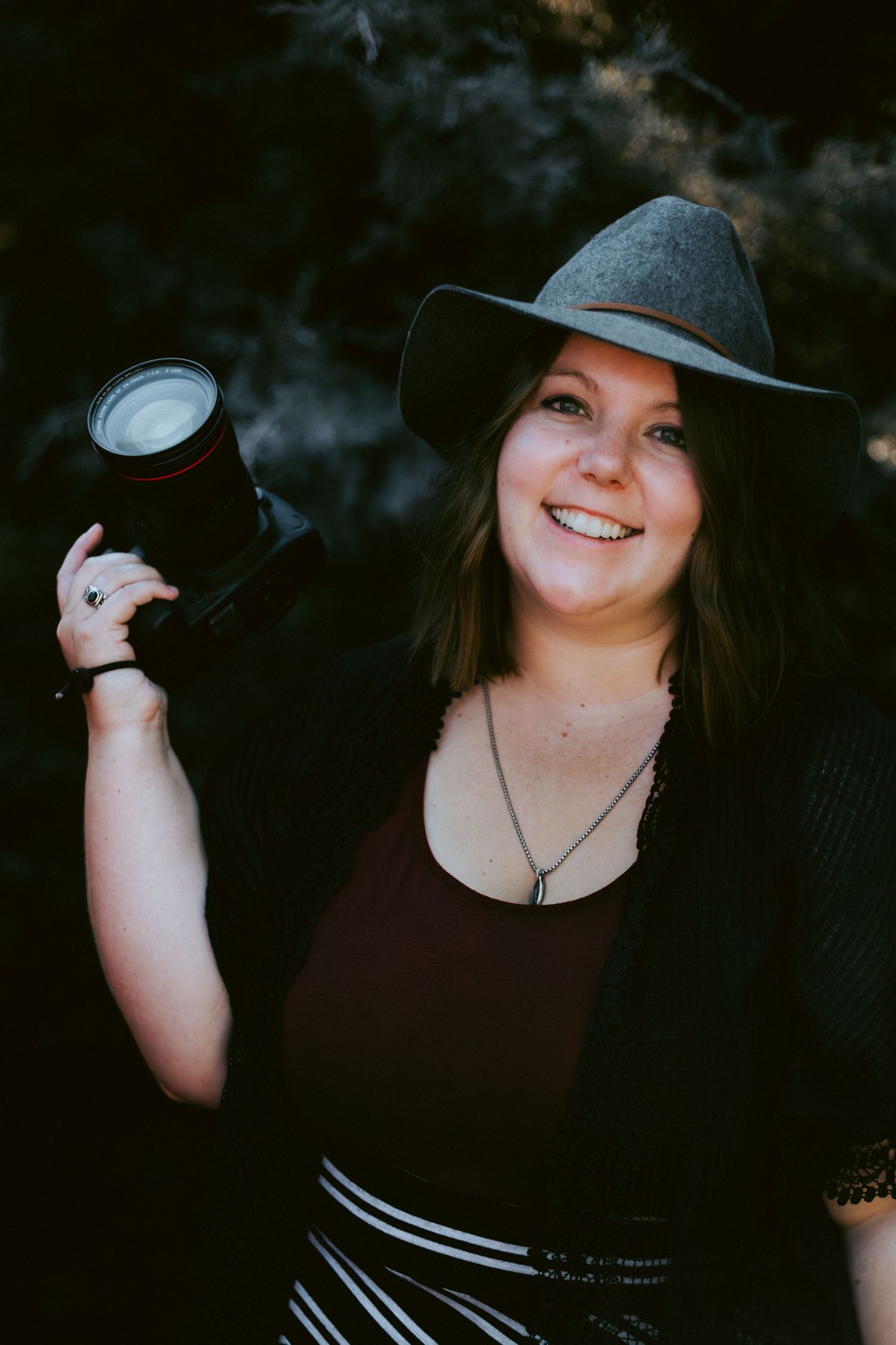 Photo of a woman in a gray hat smiling and holding a camera