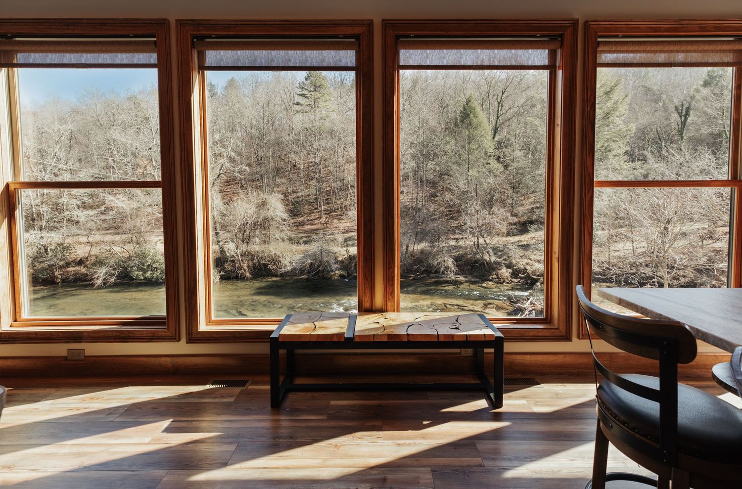 Large windows overlooking a river below with a viewing bench in center of frame.
