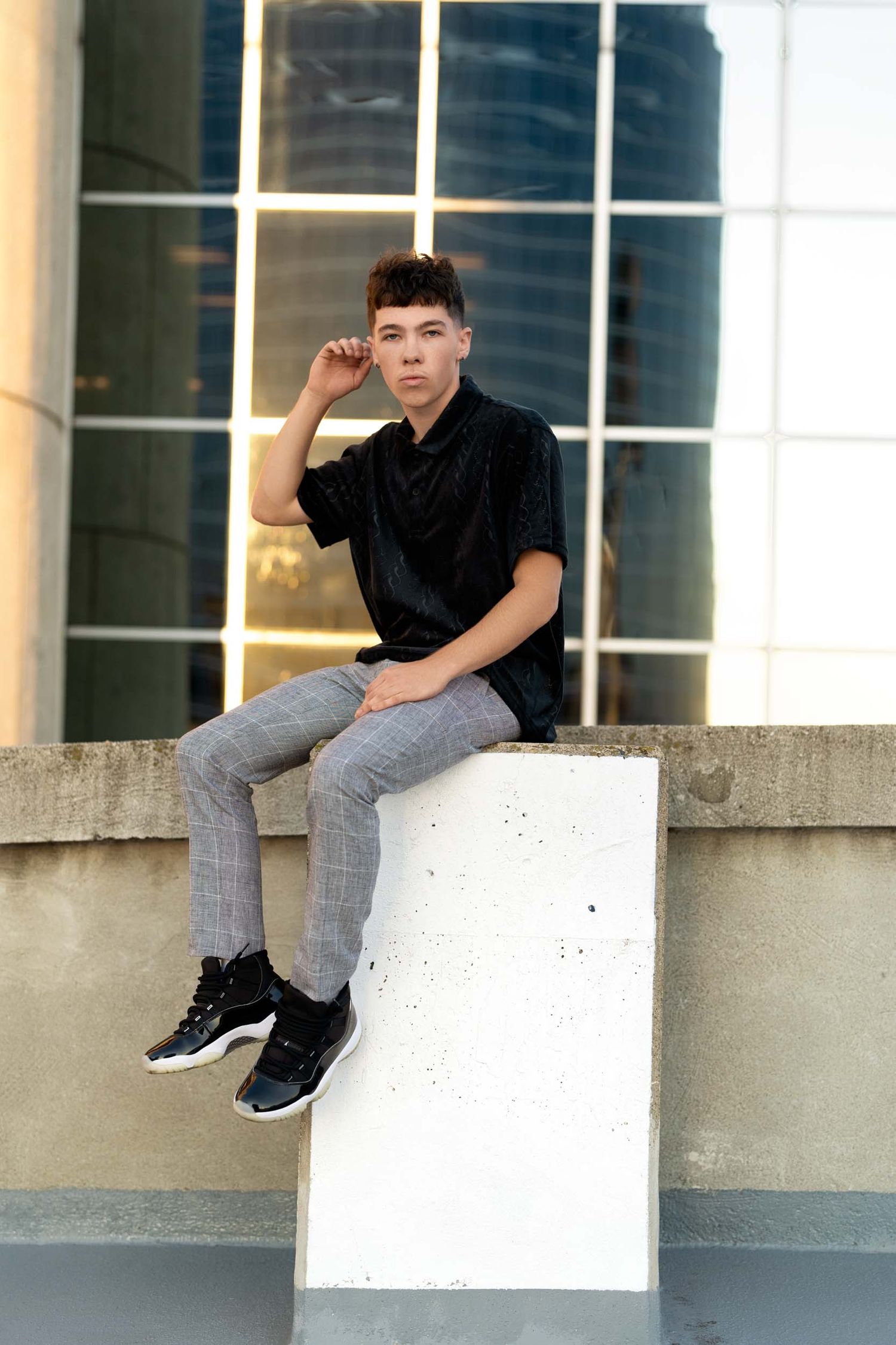 Person in black shirt and gray pants performs parkour moves on white ledge in urban setting.