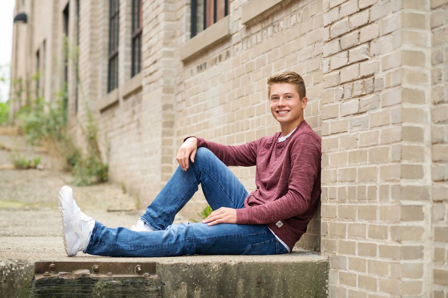 A series of senior portraits taken against a brick wall backdrop with casual poses and natural lighting.