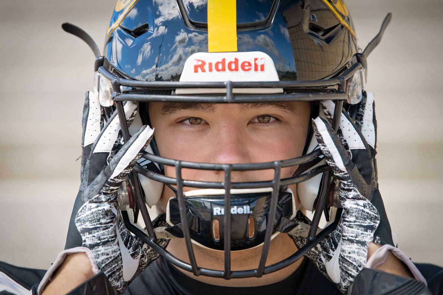 Close-up view of football helmets with blue and chrome colors showing protective face masks and Riddell branding.