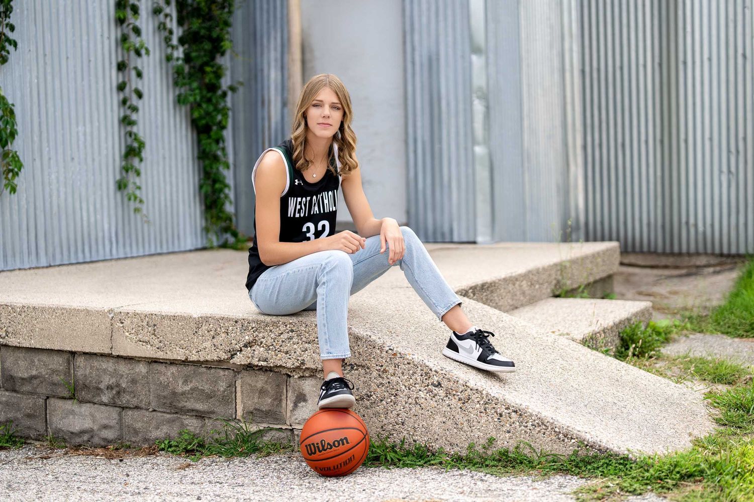 Basketball player practicing moves on concrete steps with corrugated metal wall.