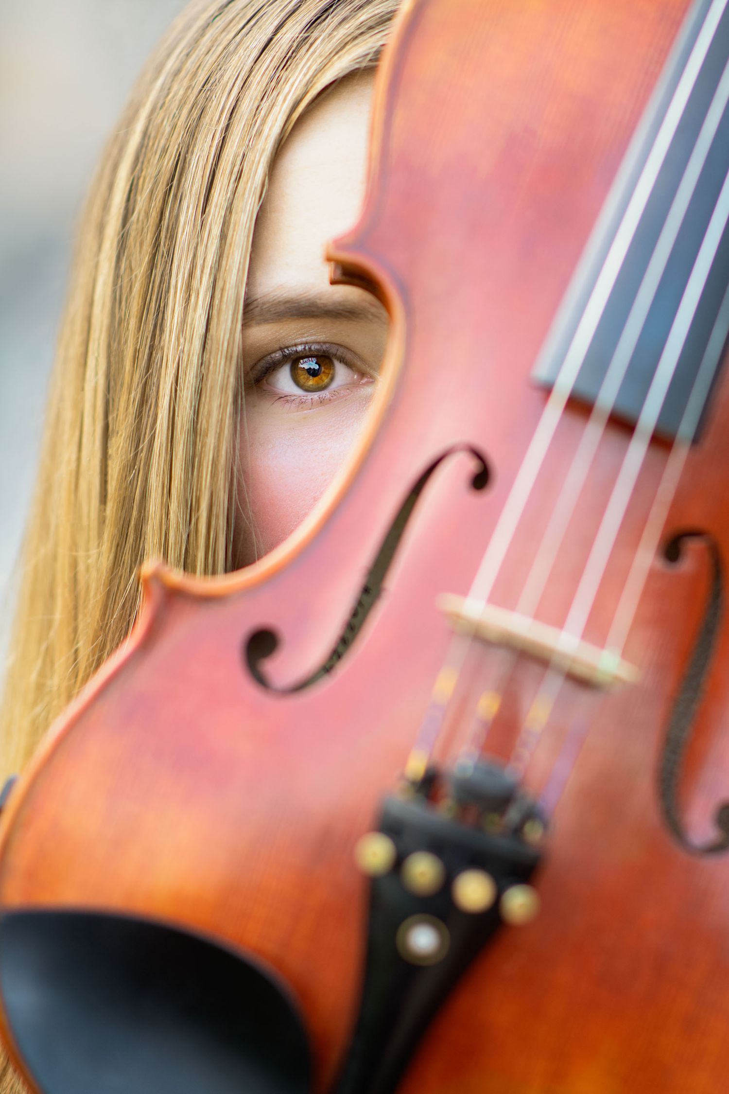 A close-up of a wooden violin with blonde hair visible in soft focus.