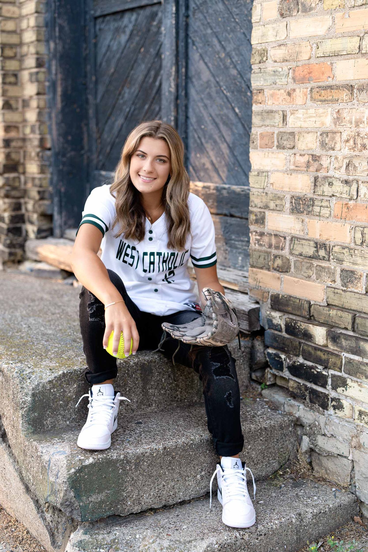 An athlete in a Westerthon jersey sits on brick steps near a rustic door.