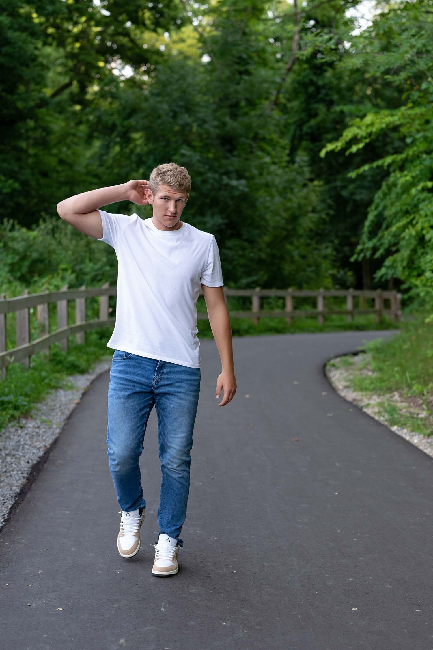 Person in white t-shirt and jeans walking along a tree-lined path demonstrating different walking poses.