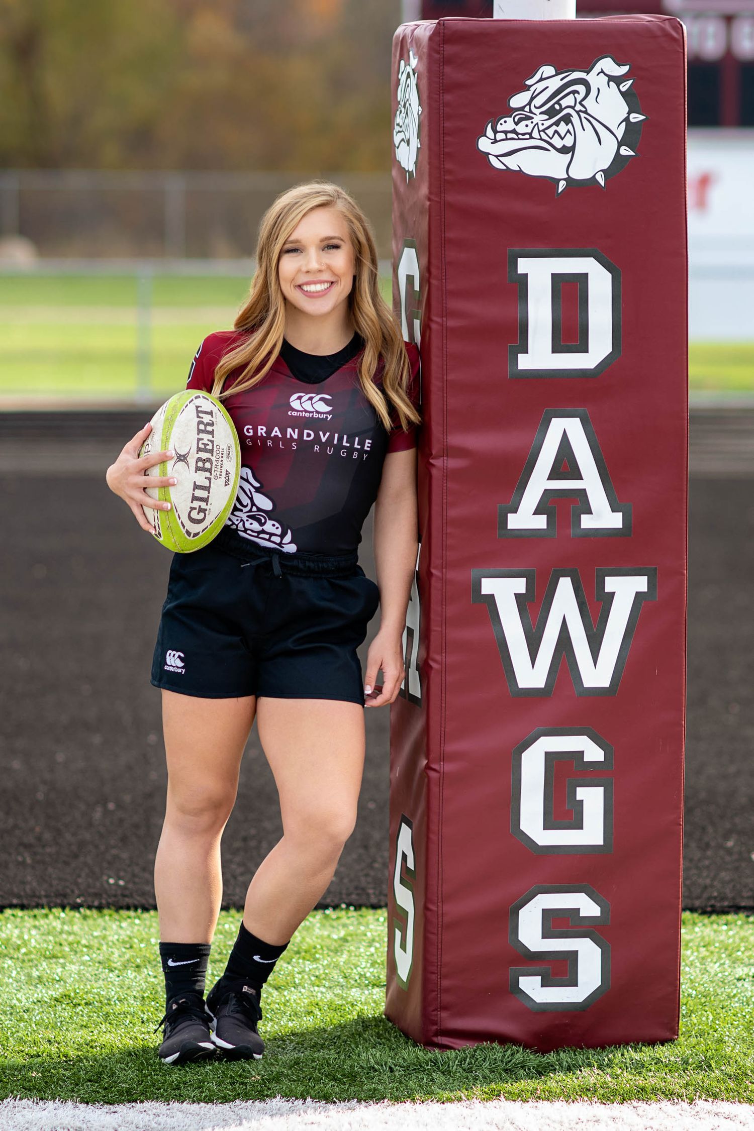 Rugby themed senior photo shoot with maroon and white tackle pads.