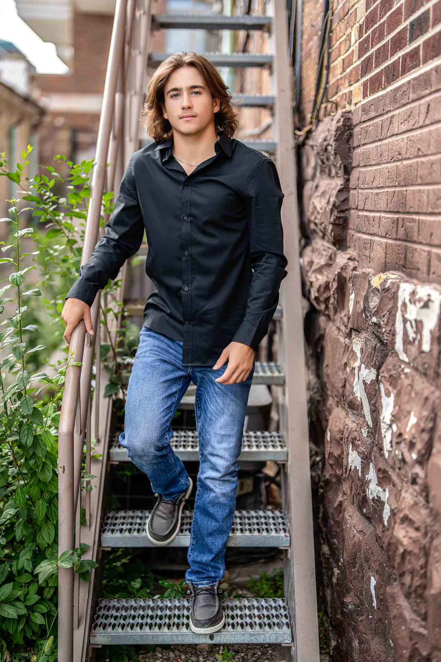 Casual portrait sequence on urban metal stairs with brick wall background.