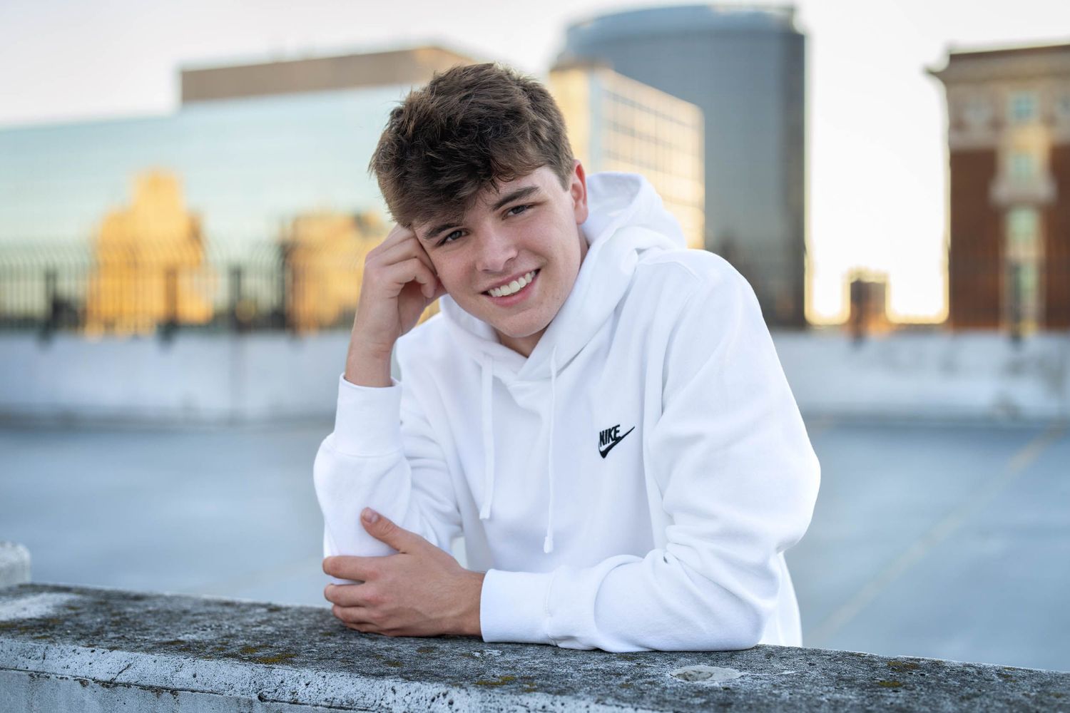 A person in a white hoodie sits outdoors smiling and looking at their phone in multiple candid poses.
